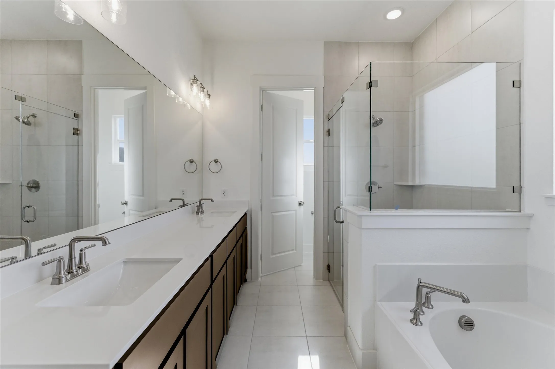Bathroom with double vanity, a stall shower, light tile patterned floors, and a bath