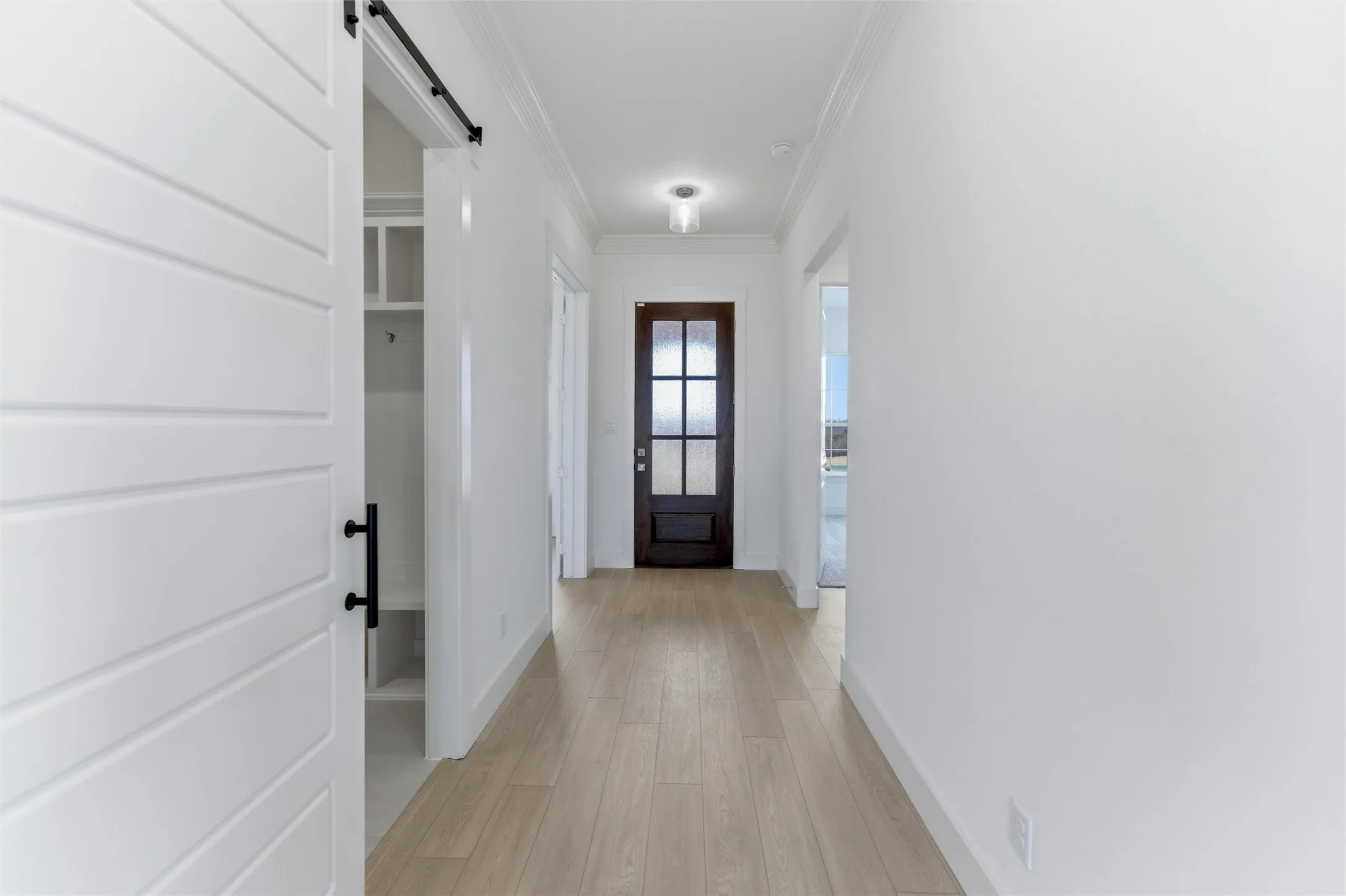 Entryway with a barn door, ornamental molding, and wood finished floors