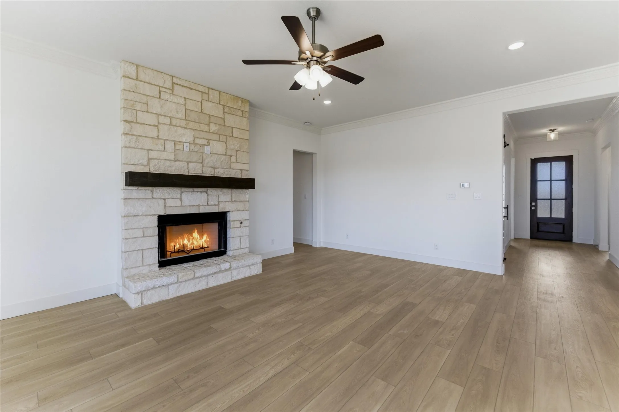 Unfurnished living room with ceiling fan, a fireplace, crown molding, light wood-style flooring, and recessed lighting