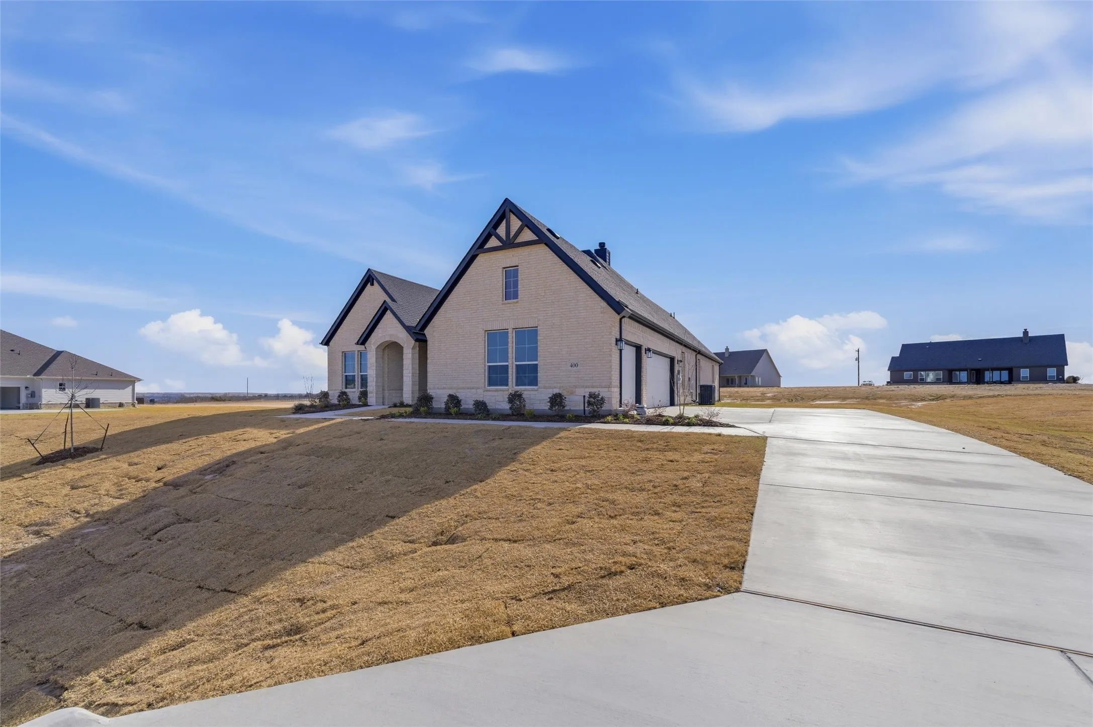 View of front of home featuring a garage, driveway, brick siding, and stone siding