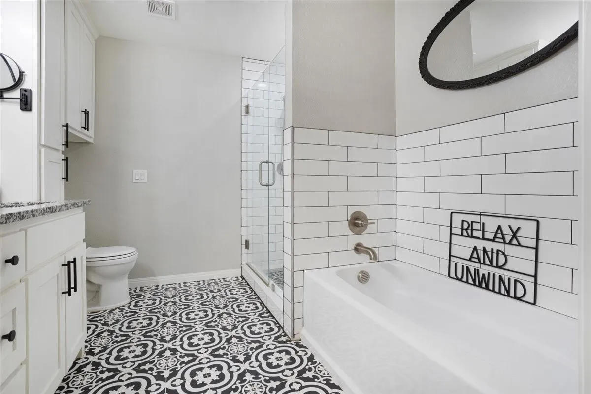 Full bathroom featuring a garden tub, vanity, a stall shower, and light tile patterned floors