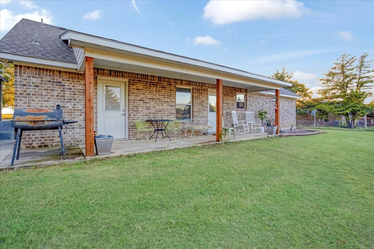 Rear view of property featuring brick siding, a yard, and a shingled roof