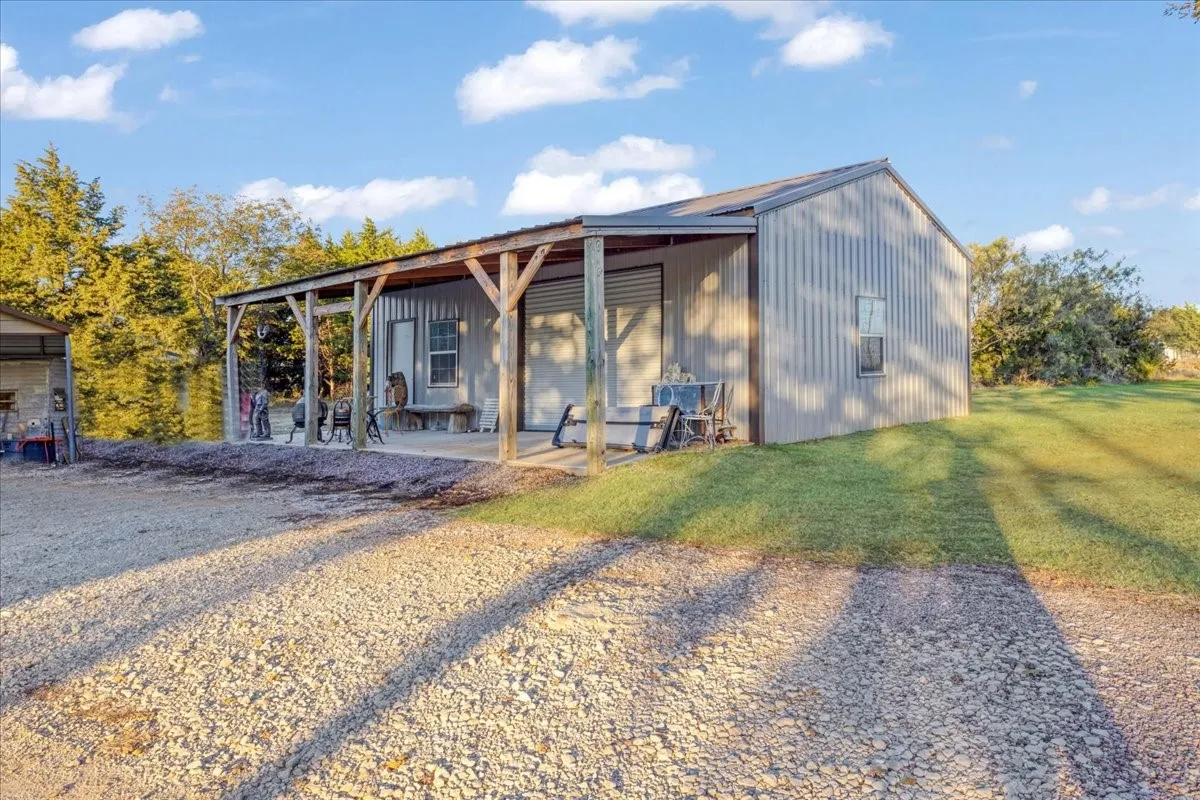 View of front of house featuring an outbuilding, a front yard, a patio area, and board and batten siding