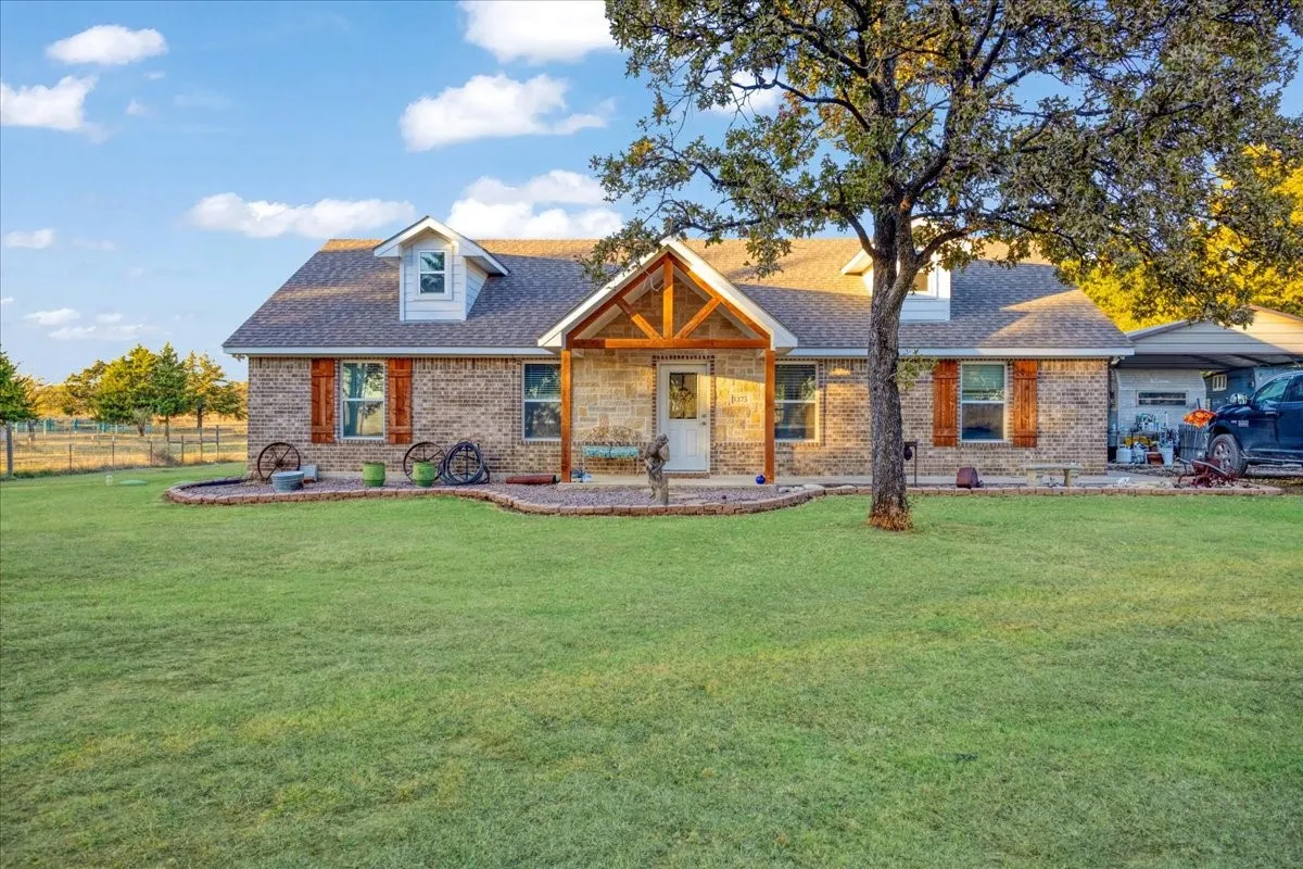 View of front of house with covered porch, brick siding, and a shingled roof