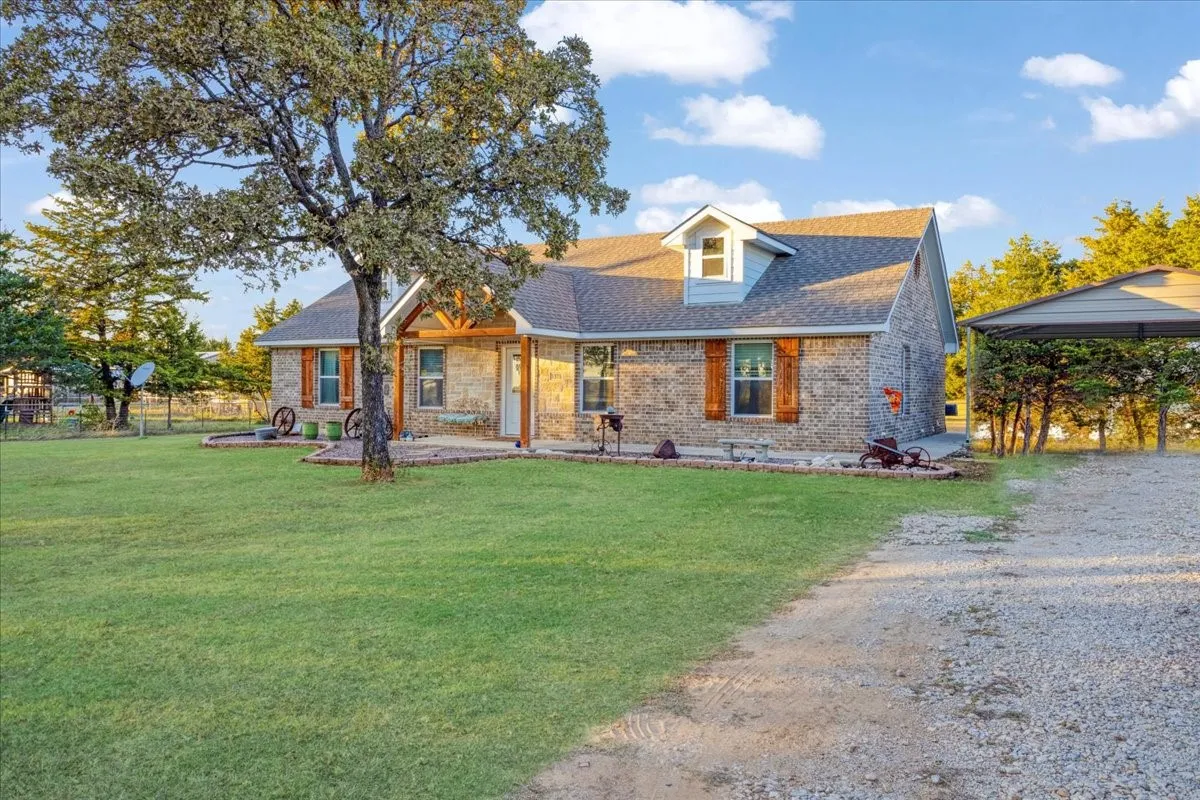 View of front of home featuring a front lawn, a shingled roof, brick siding, and driveway