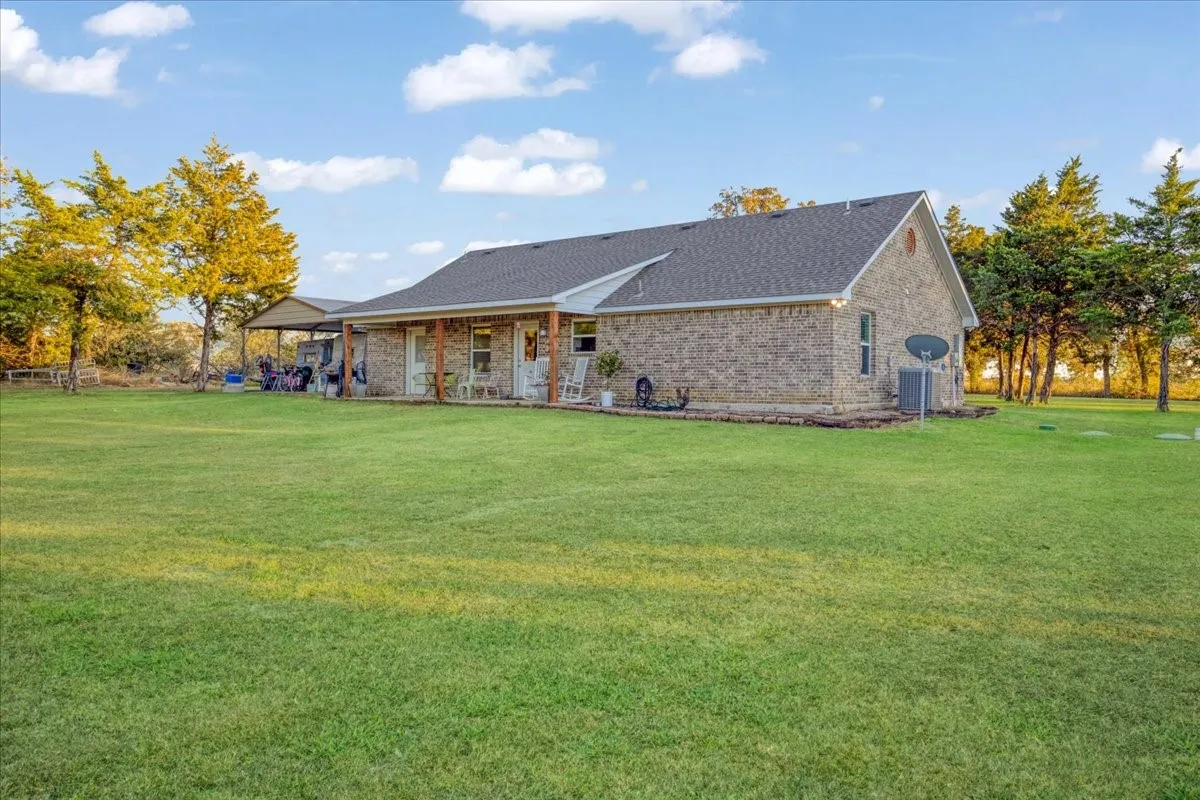 Back of house with a yard, brick siding, and a shingled roof