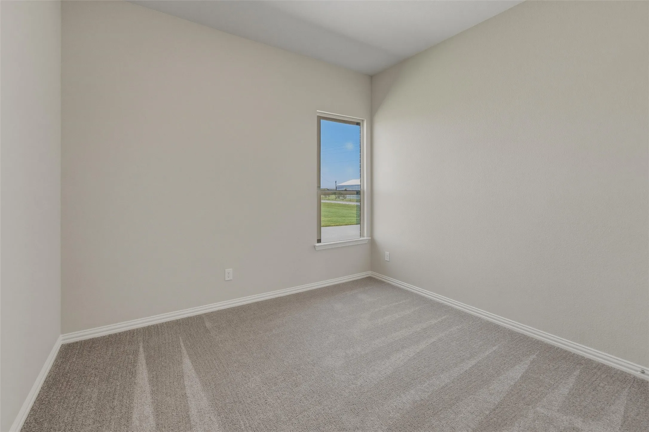 Neutral-toned room featuring a single window and textured carpeting