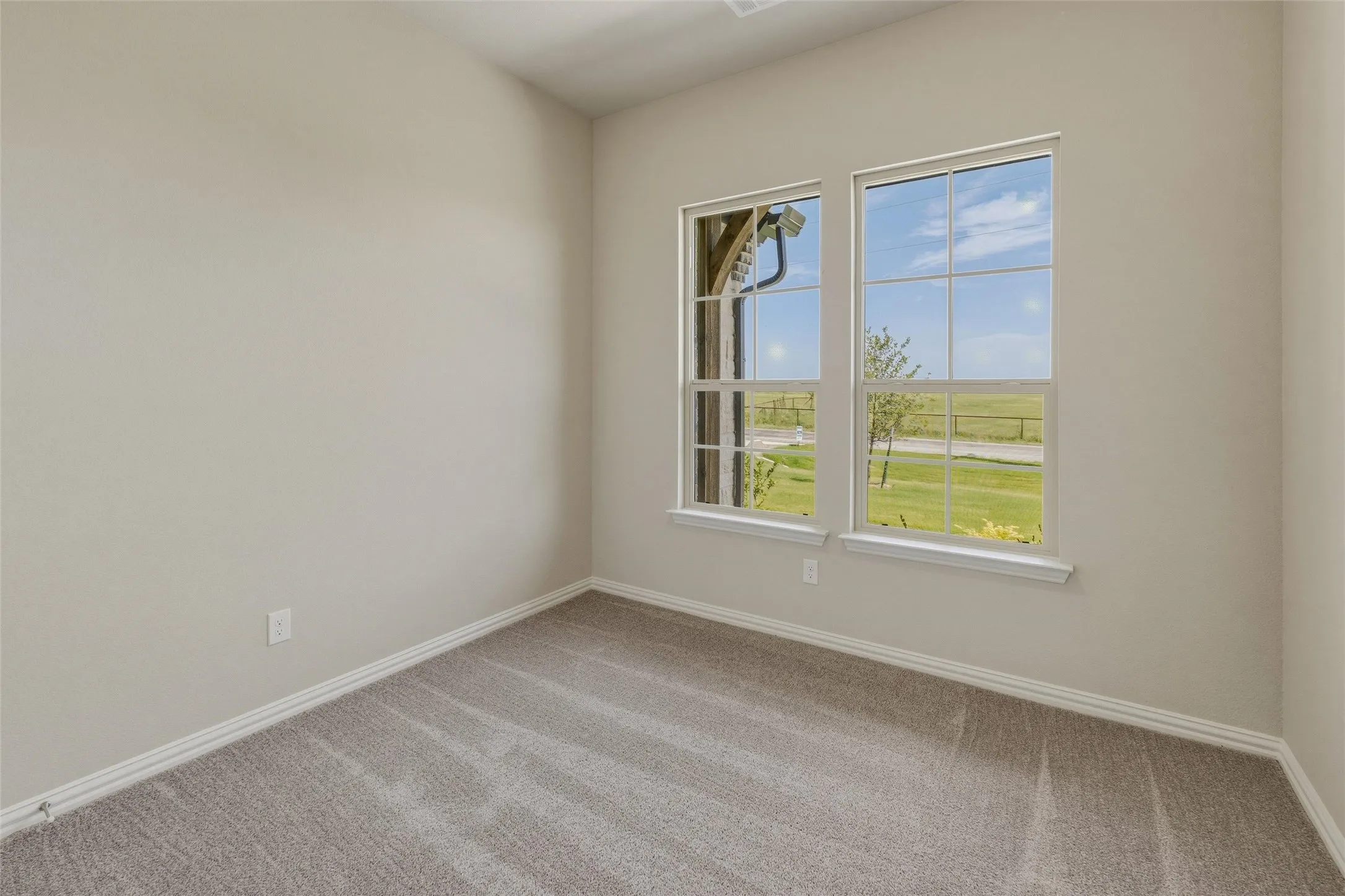 Room featuring light-toned wall paint, two large windows, white window trim, and a gray carpeted floor