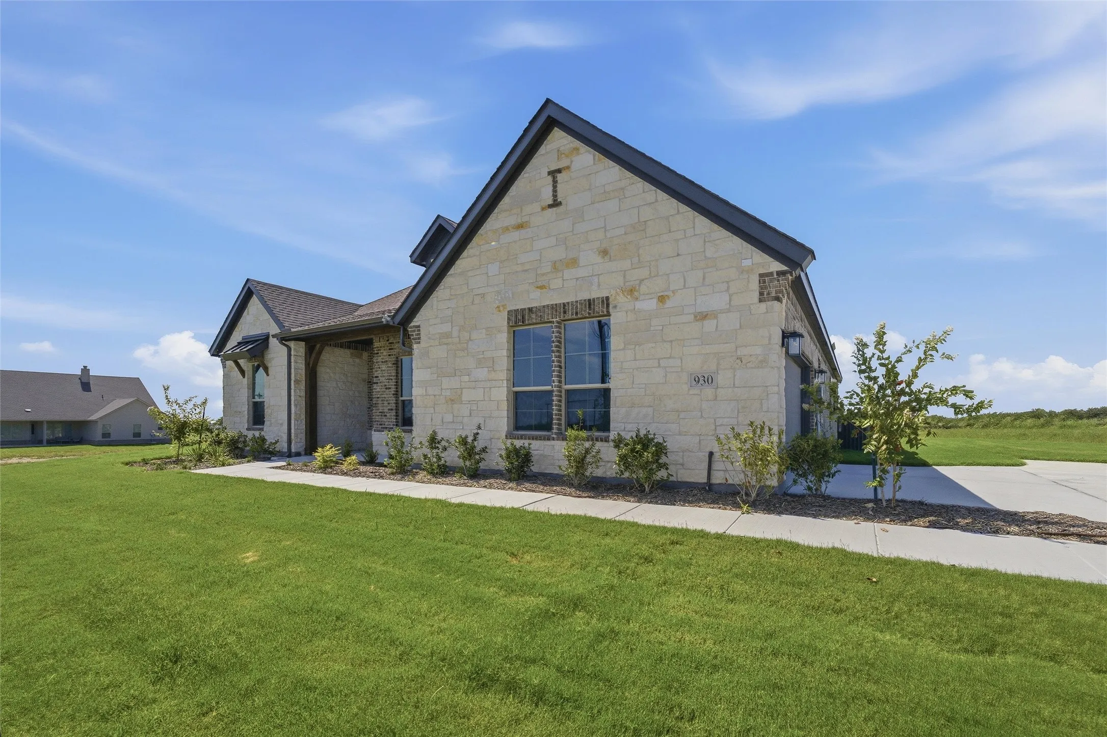 Stone facade home featuring dark trim, a covered entry, and an attached garage