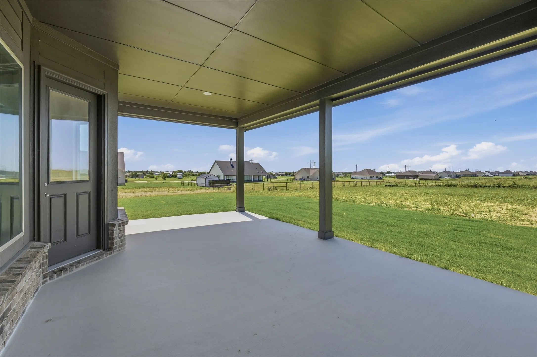 Spacious covered patio featuring a smooth concrete surface, recessed lighting, and support columns