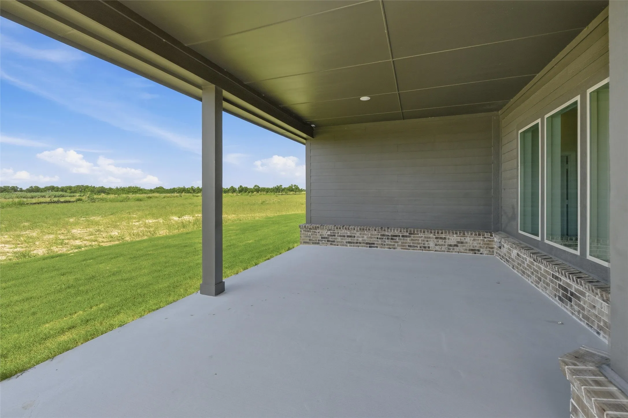Expansive covered patio featuring a concrete floor, recessed lighting, and support columns