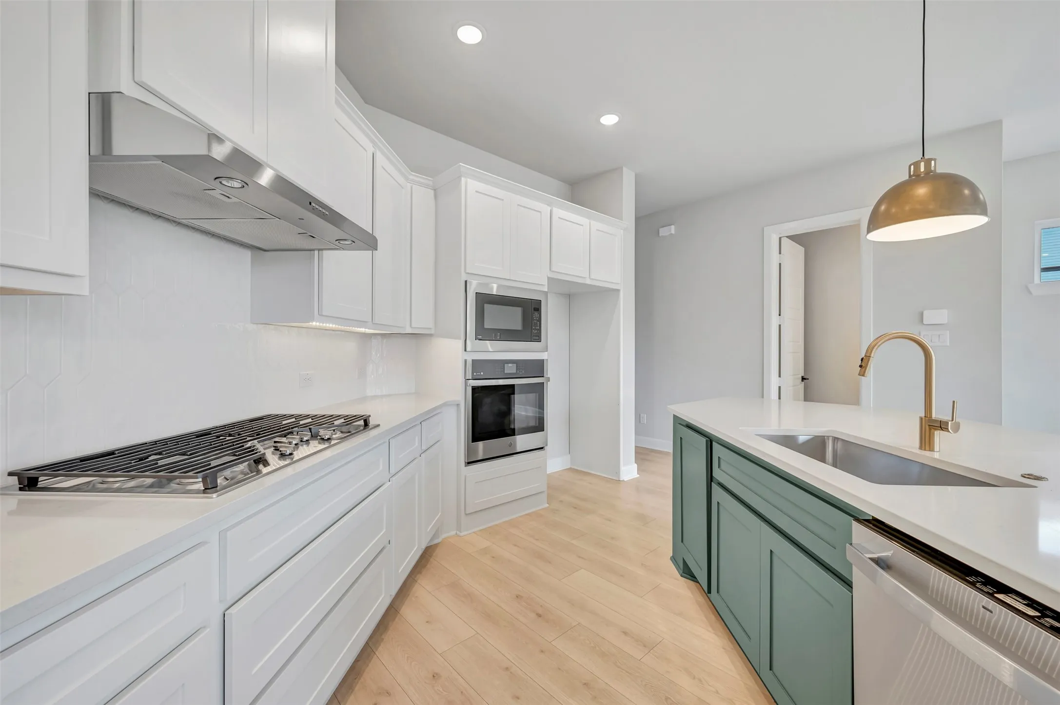 Two tone kitchen featuring two tone color scheme, stainless steel appliances, light wood-style floors, light stone countertops, and hanging light fixtures