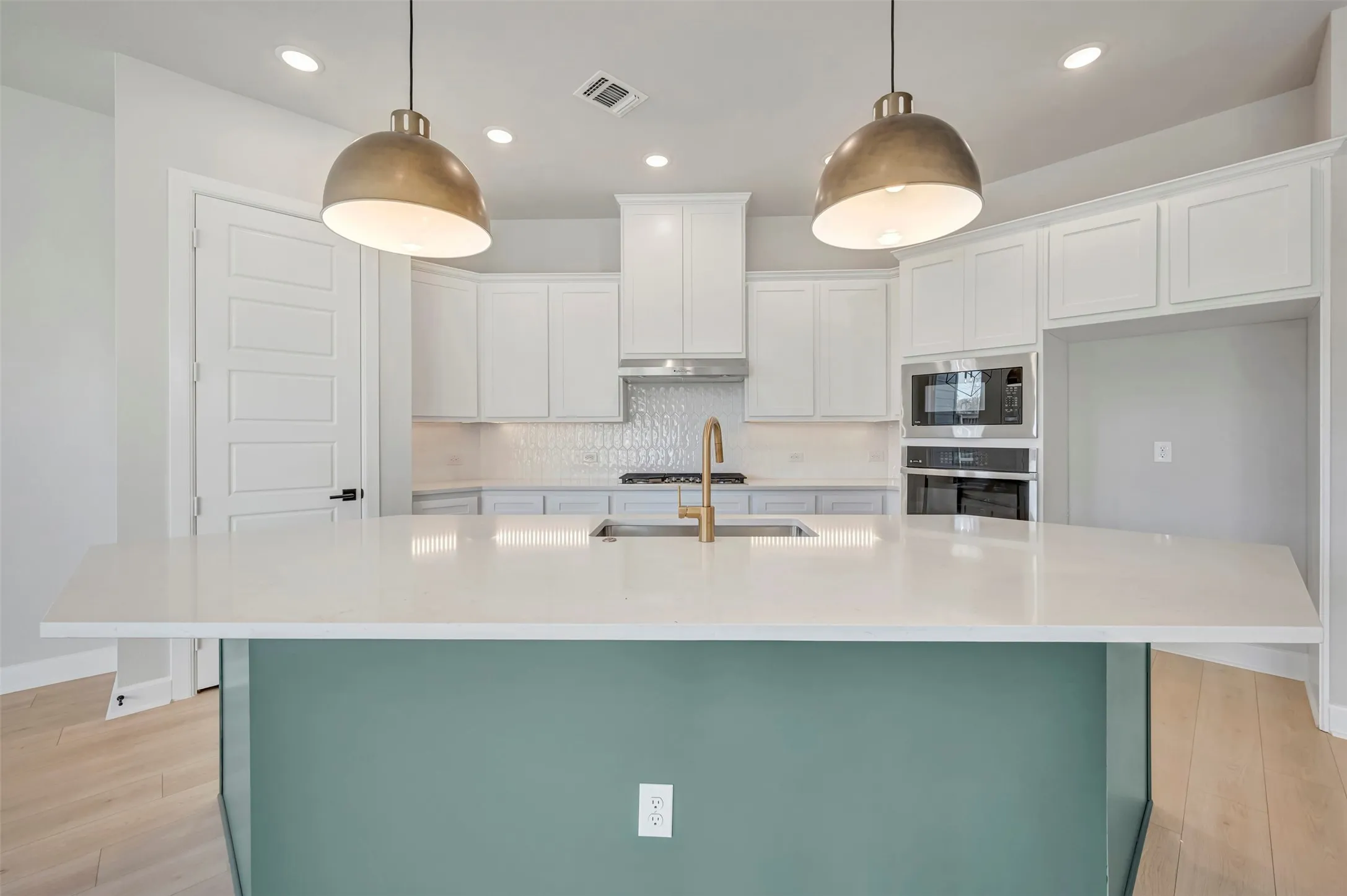 Kitchen with backsplash, light wood-type flooring, a kitchen island with sink, stainless steel appliances, and dual tone cabinets