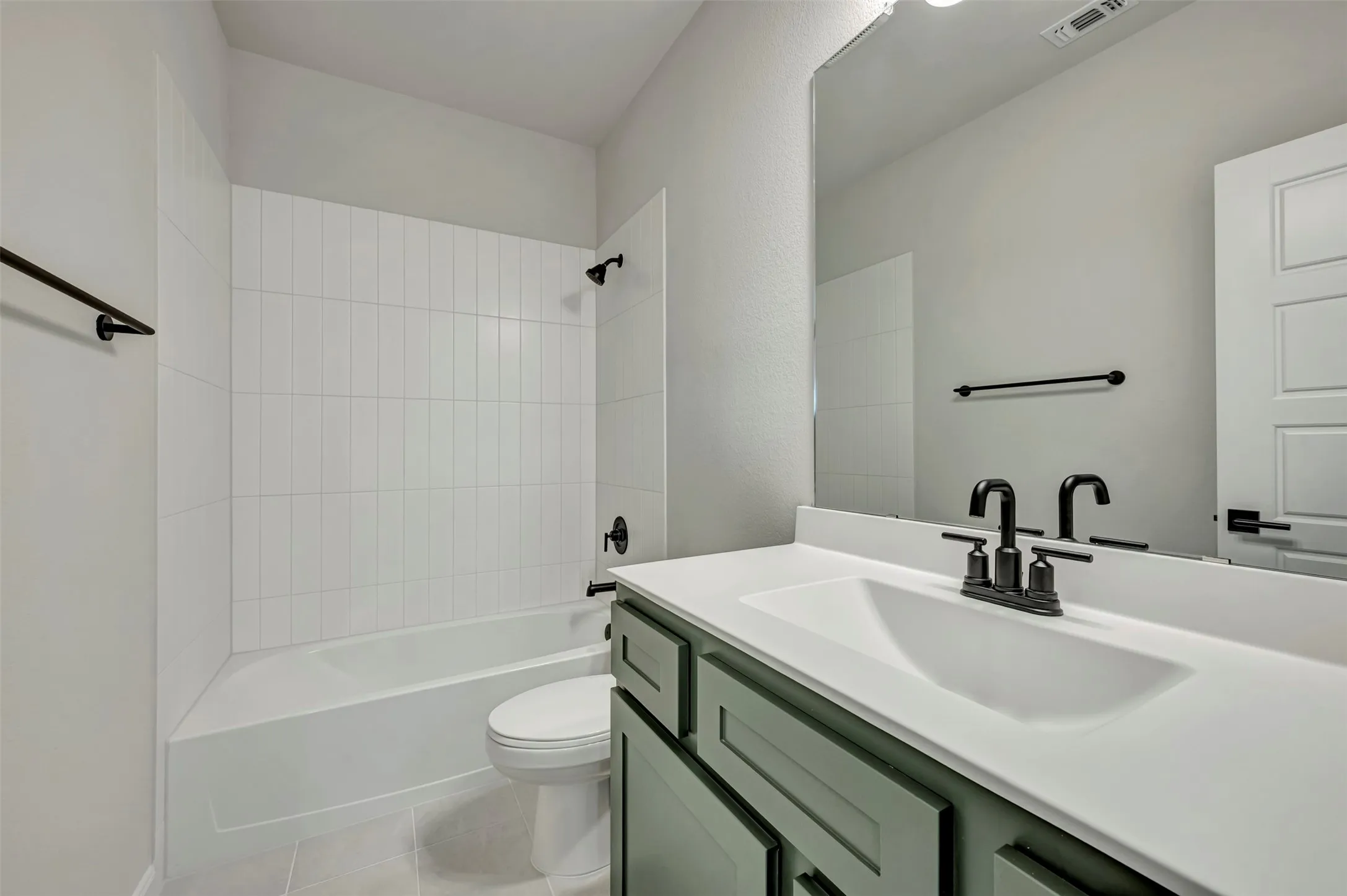 Bathroom with vanity, washtub / shower combination, and light tile patterned flooring
