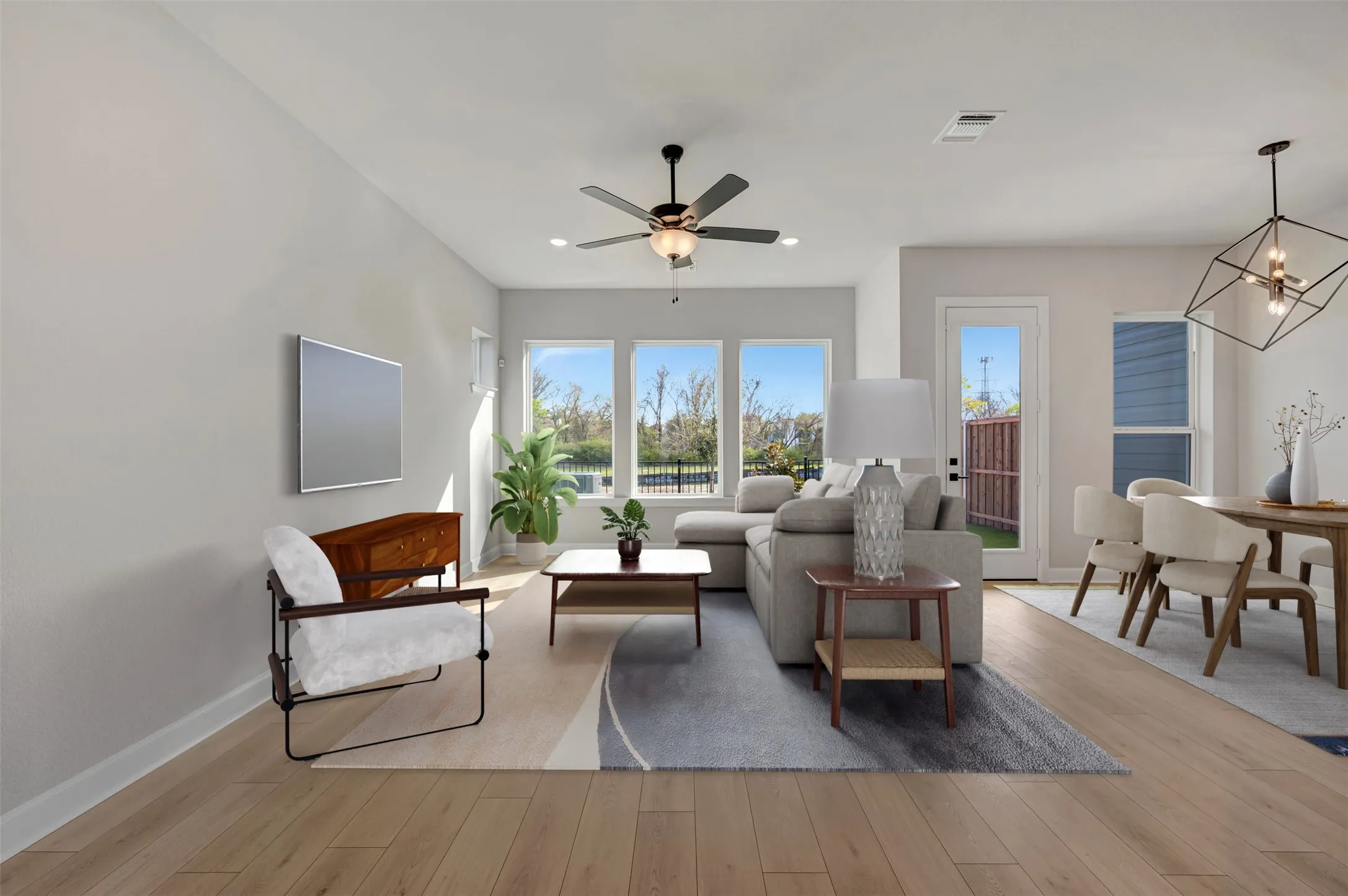 Living room featuring hanging lights, light wood-type flooring, and a ceiling fan