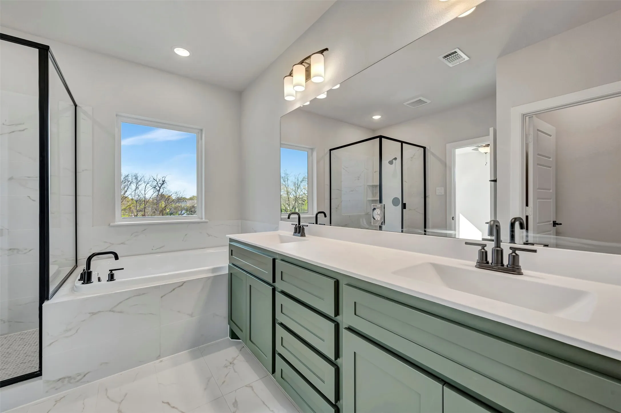 Full bath with double vanity, a marble finish shower, a garden tub, and light marble finish flooring