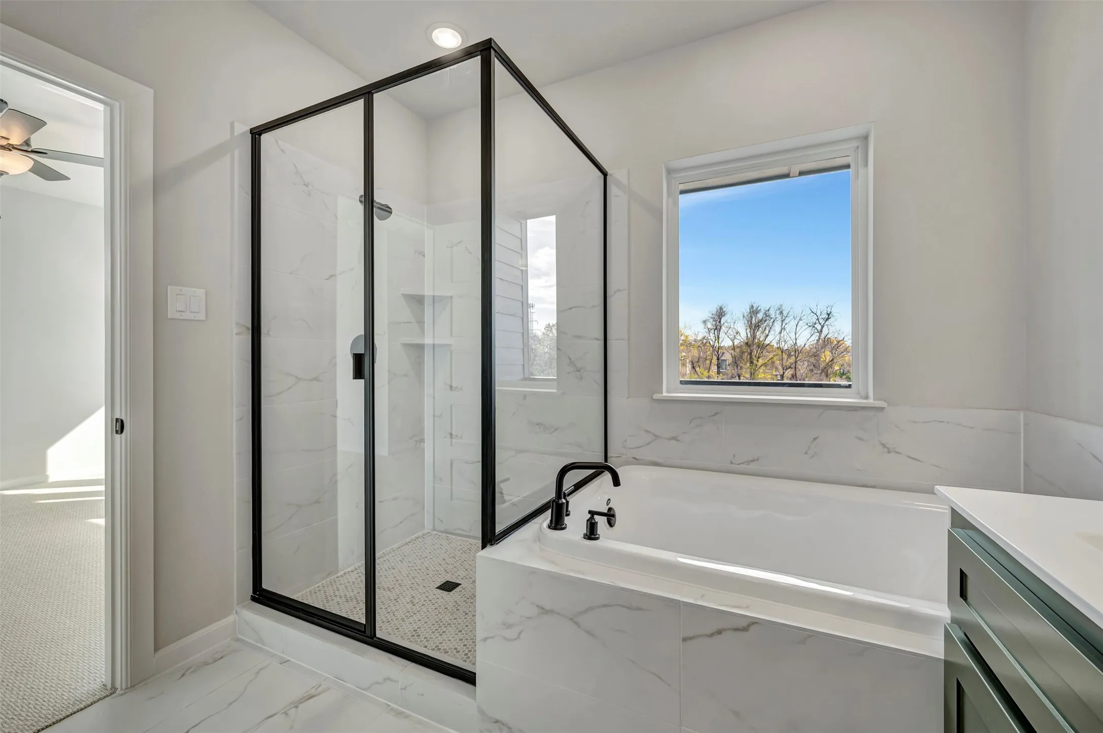 Full bathroom featuring light marble finish flooring, a marble finish shower, a garden tub, a ceiling fan, and vanity
