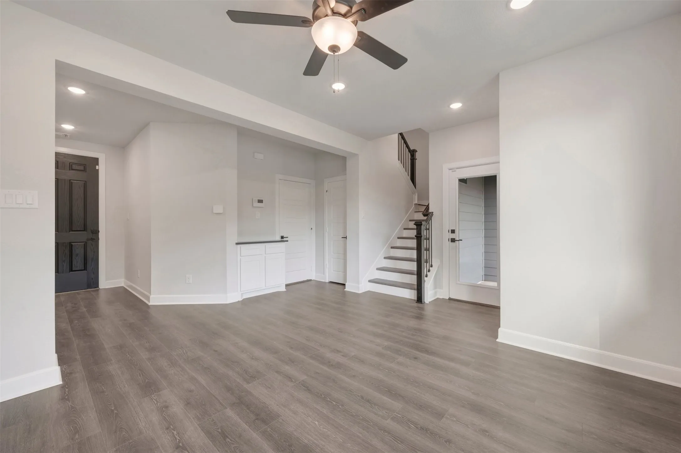 Spacious living area featuring wood-finish flooring, recessed lighting, and a ceiling fan with integrated lighting