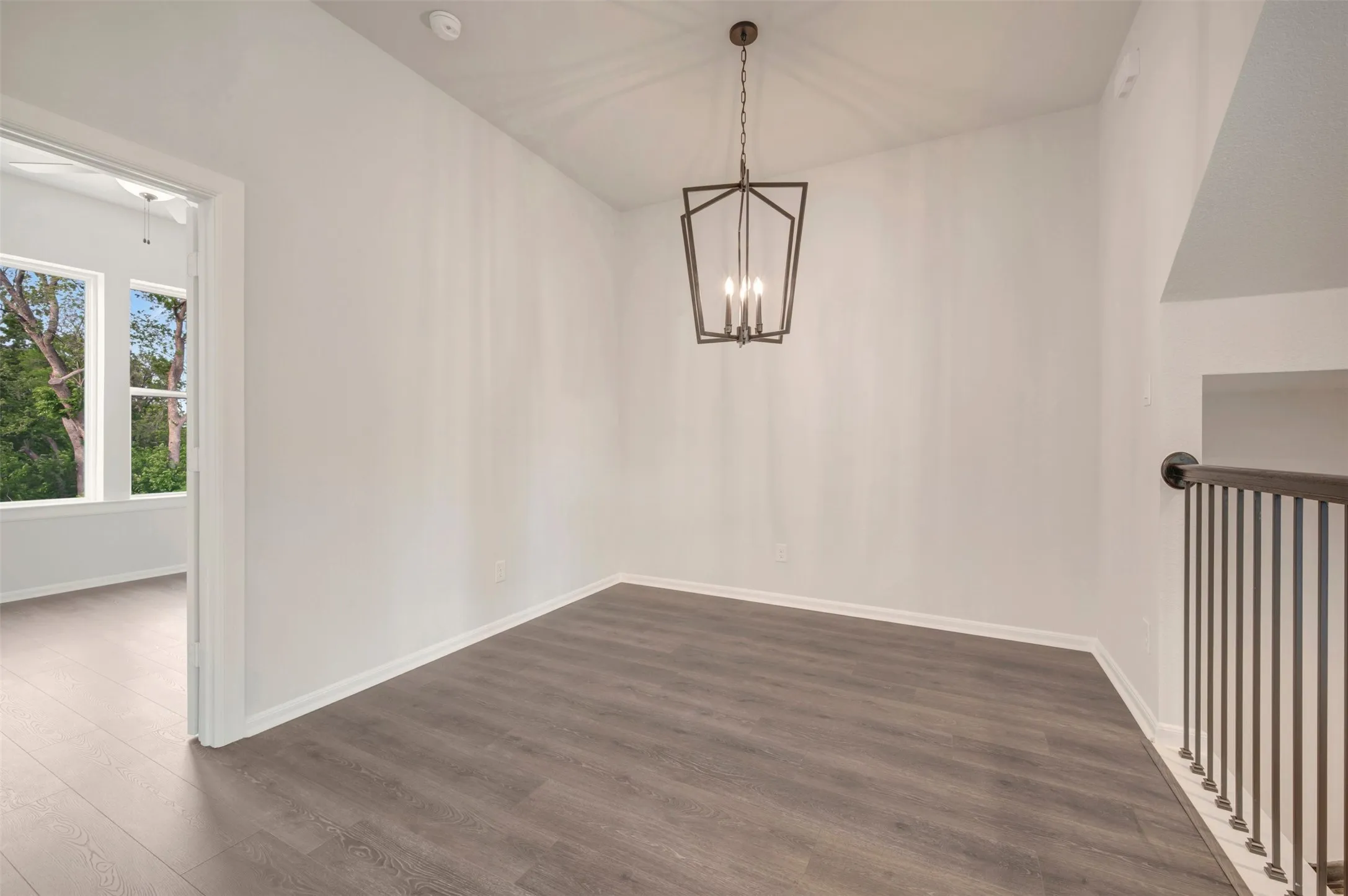 Interior space featuring wood-finish flooring, white walls, and a contemporary geometric chandelier