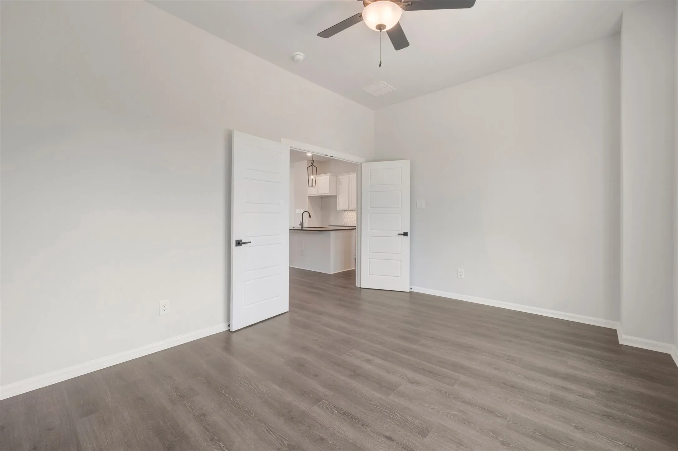 Spacious room featuring gray wood-finish flooring and a contemporary ceiling fan with integrated lighting