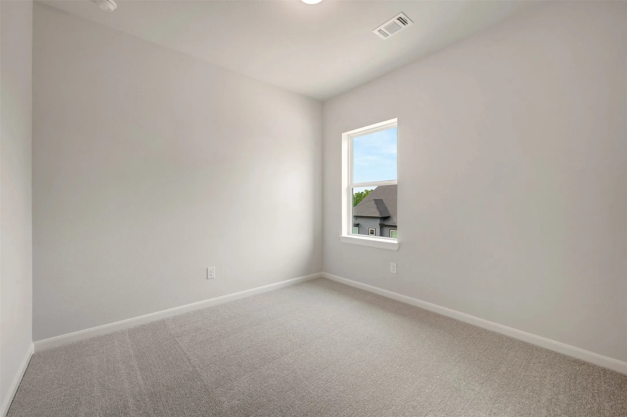 Carpeted interior space featuring light-toned walls, white trim, and a prominent window