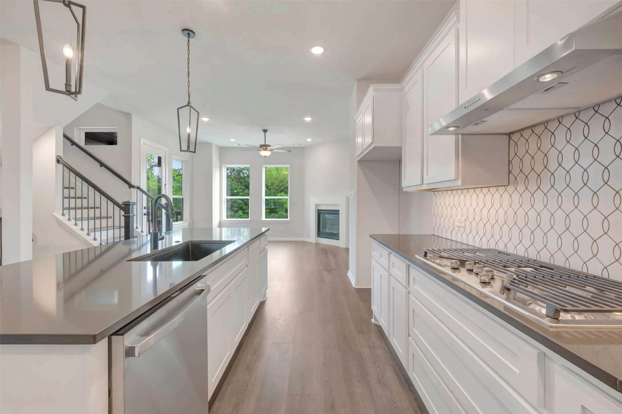 Contemporary kitchen featuring white cabinetry, dark countertops, and a gas cooktop with a stainless steel range hood