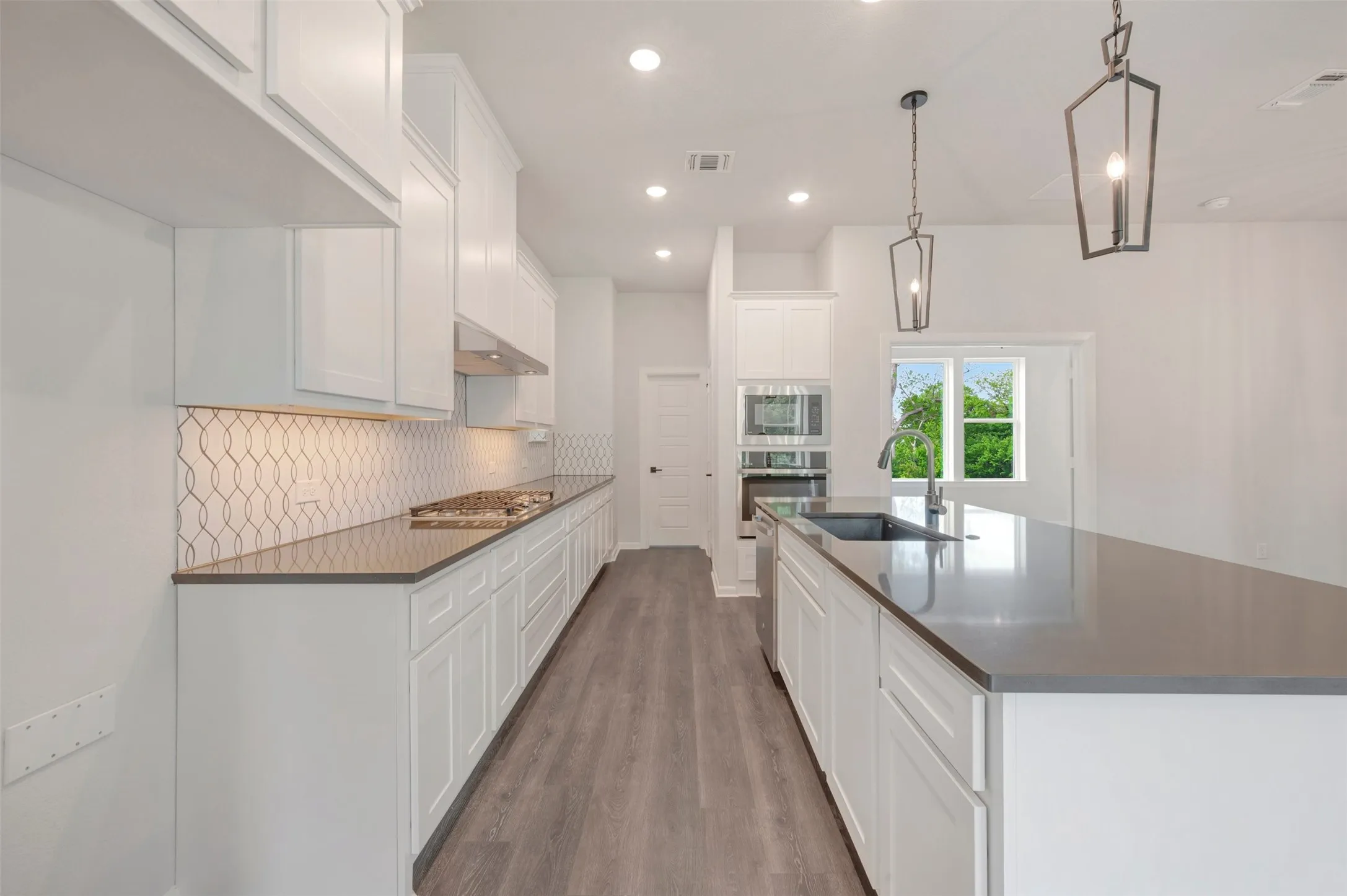 Contemporary kitchen featuring white cabinetry and light wood-finish flooring