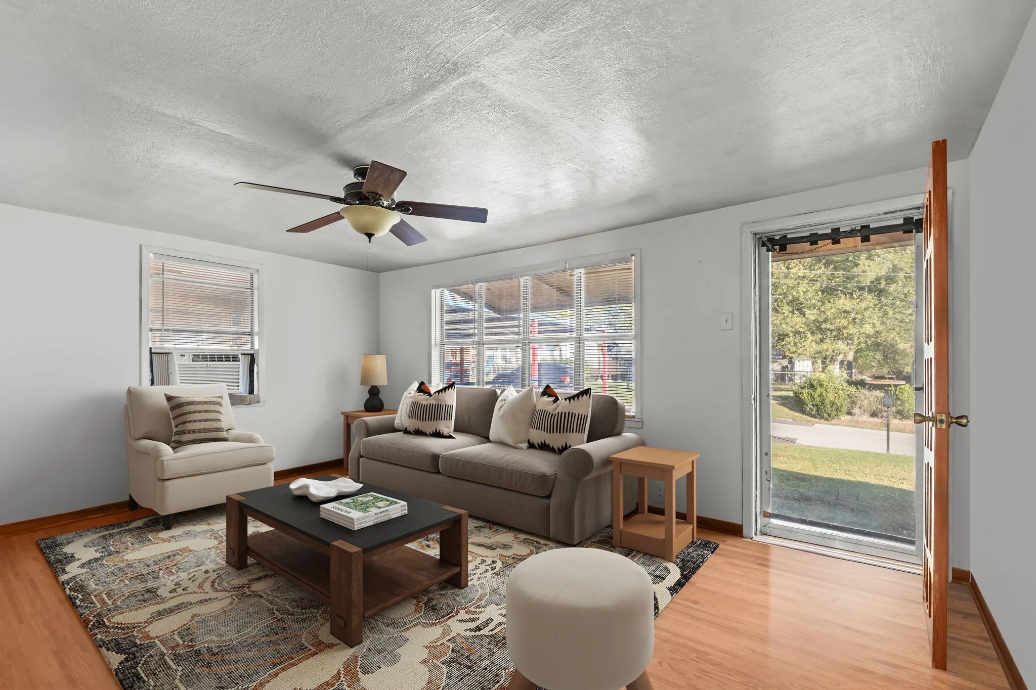 Living area featuring light wood-style floors, a textured ceiling, a ceiling fan, and cooling unit
