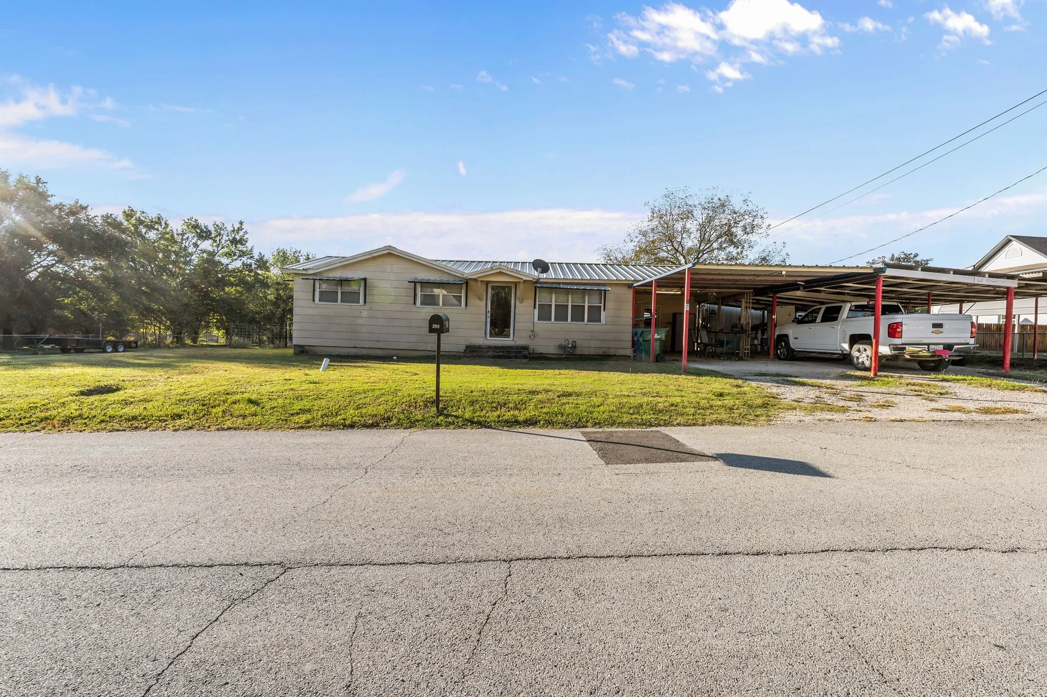 Ranch-style house with a front yard, an attached carport, driveway, and a metal roof