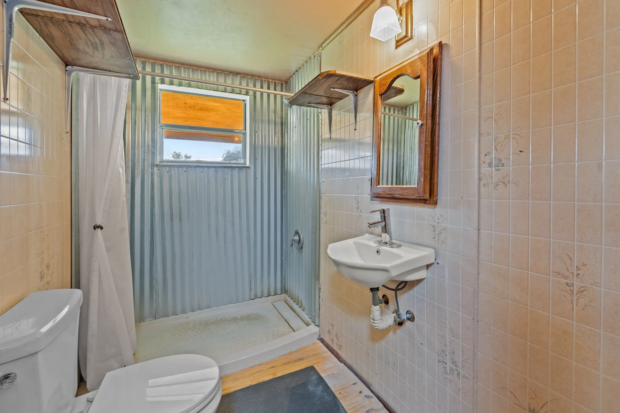 Bathroom with tile walls, a shower stall, and wood finished floors