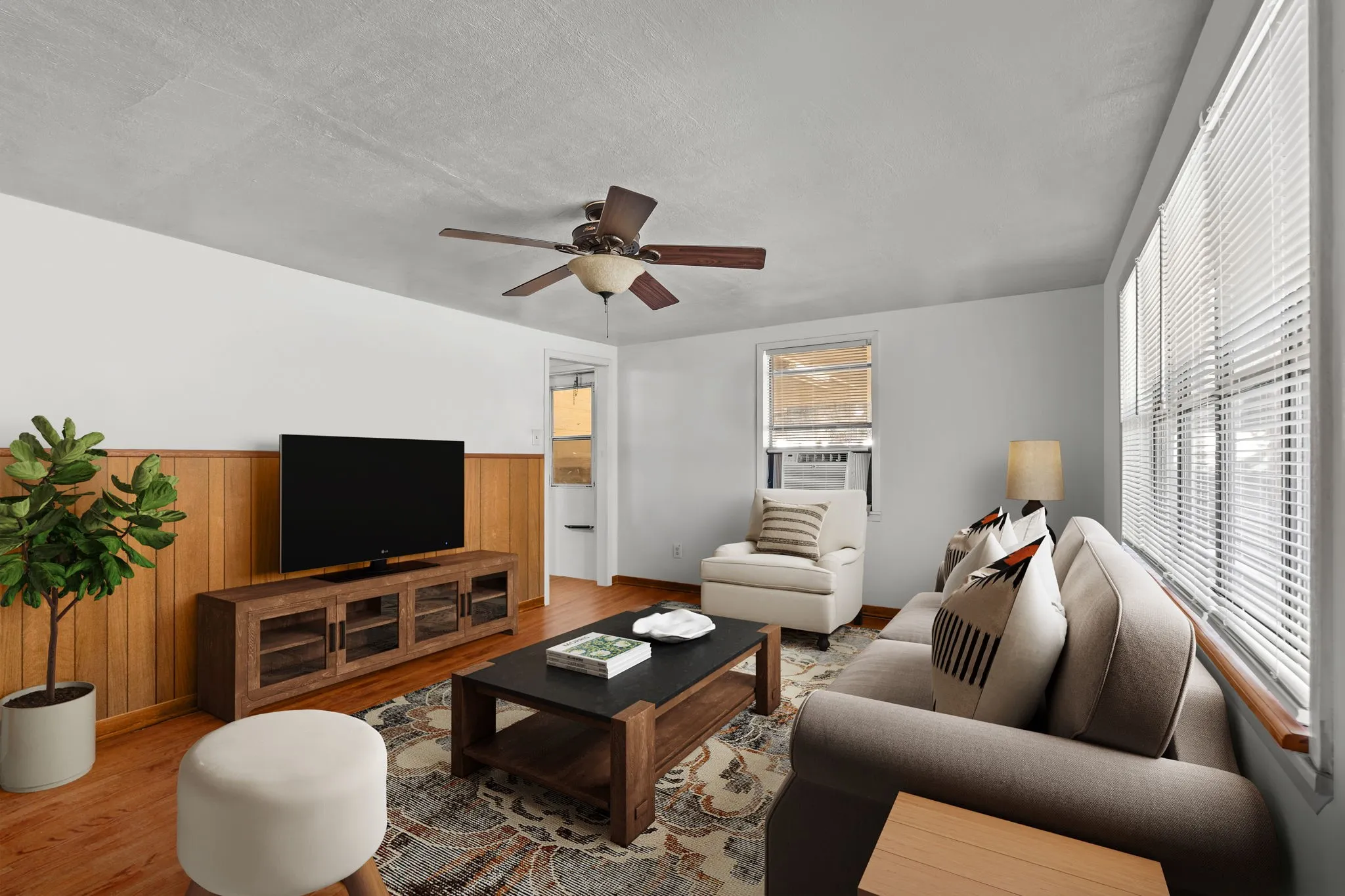 Living room featuring wood walls, wood finished floors, a wainscoted wall, ceiling fan, and a textured ceiling