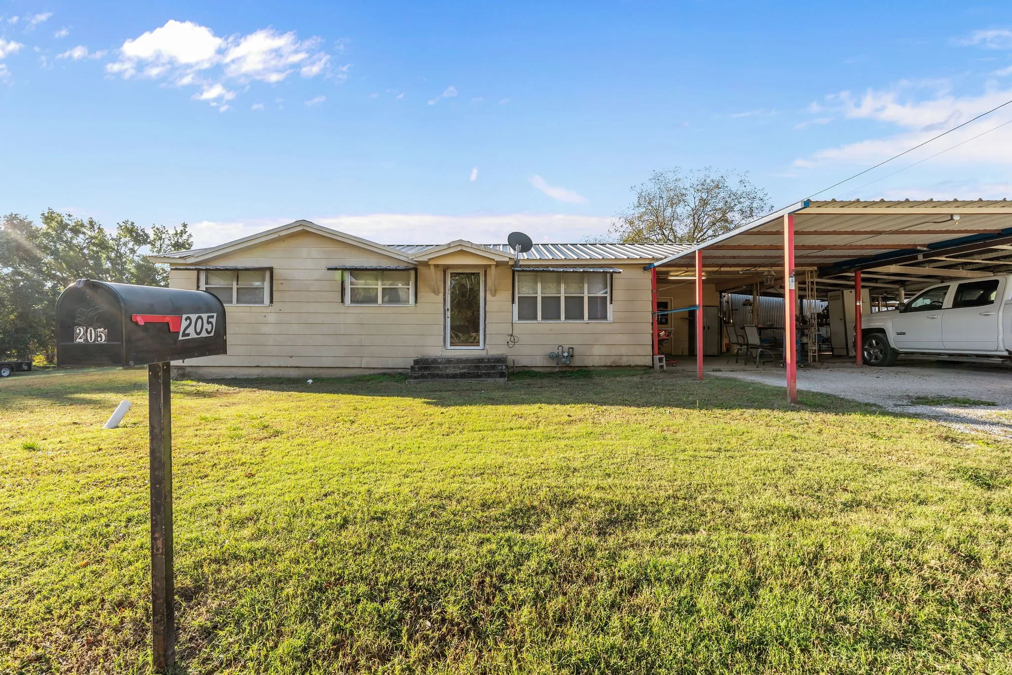 Single story home with a metal roof, a front lawn, a carport, and entry steps