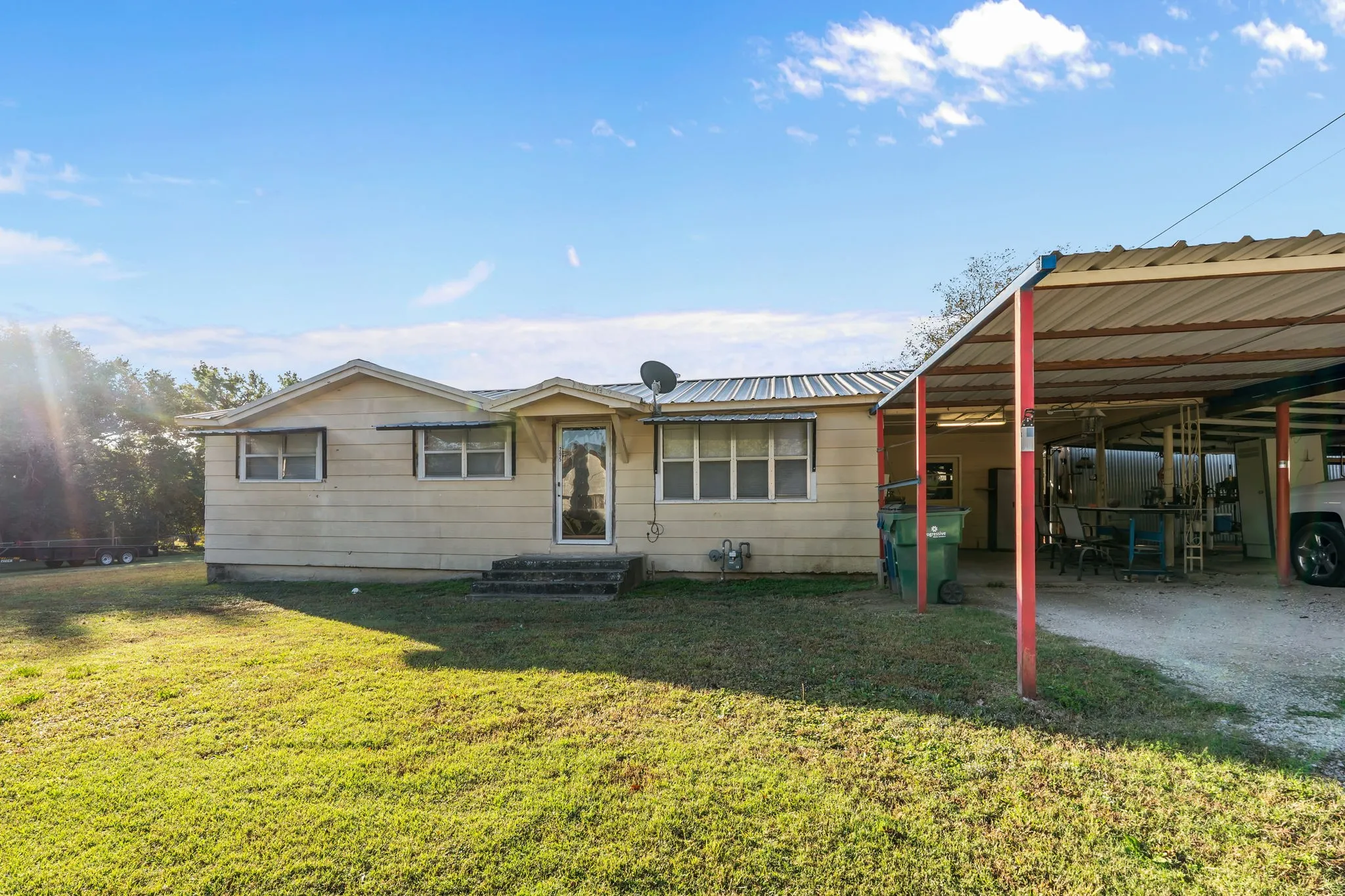 View of front of property with a front yard, a carport, and a metal roof