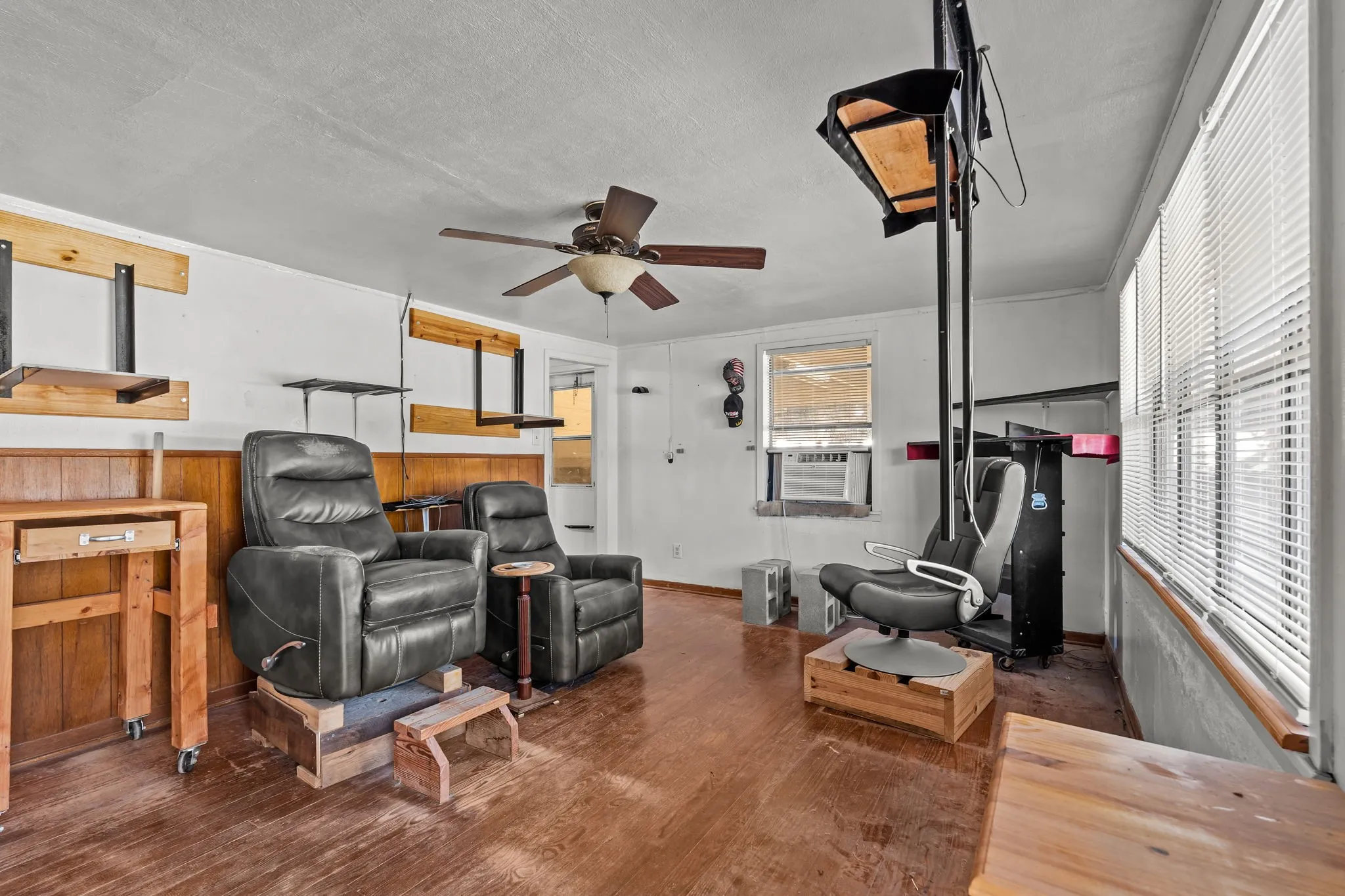 Living area with dark wood-style flooring, a textured ceiling, ceiling fan, and wooden walls