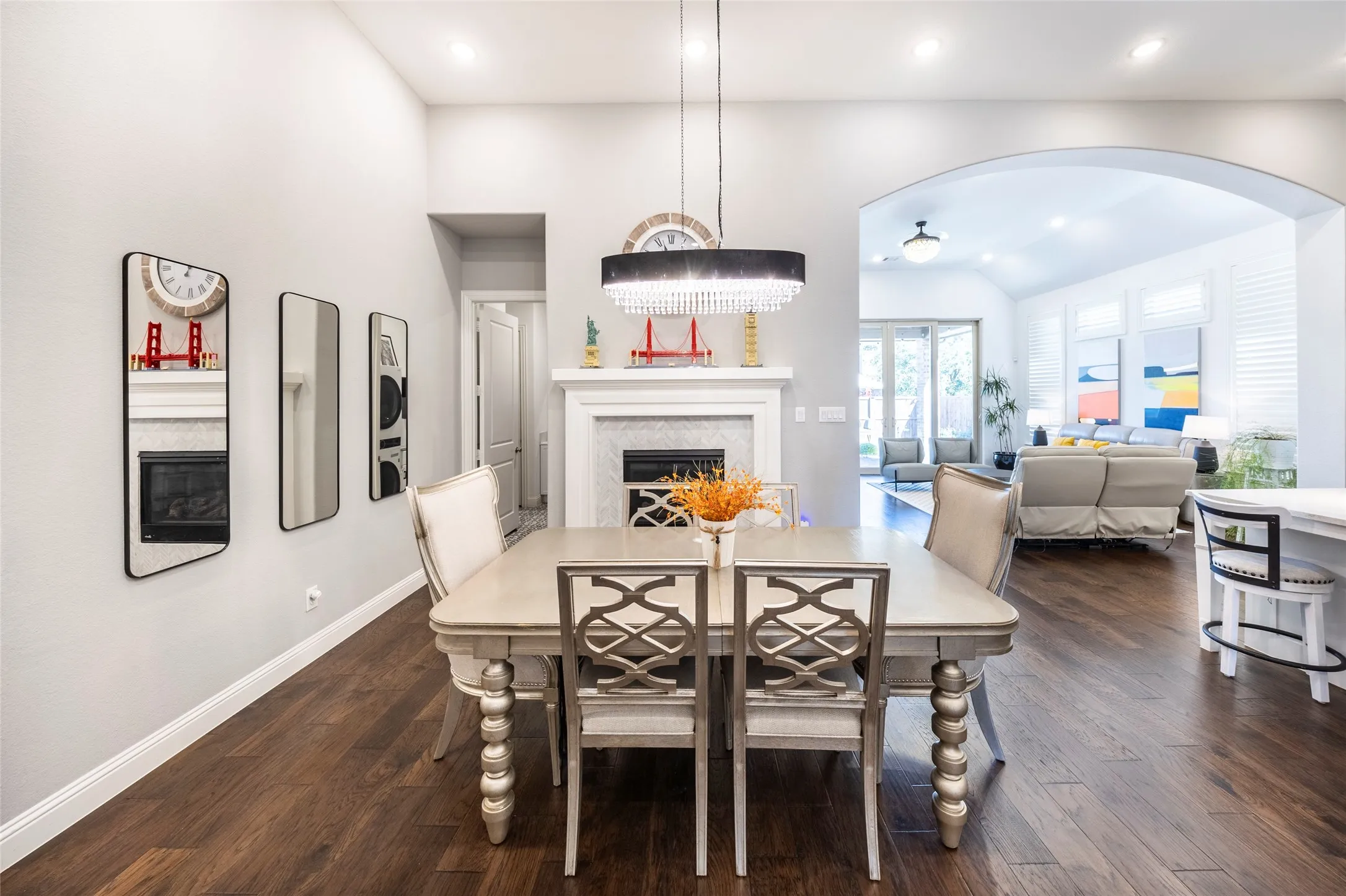 Dining space featuring a glass covered fireplace, vaulted ceiling, dark wood-type flooring, recessed lighting, and arched walkways