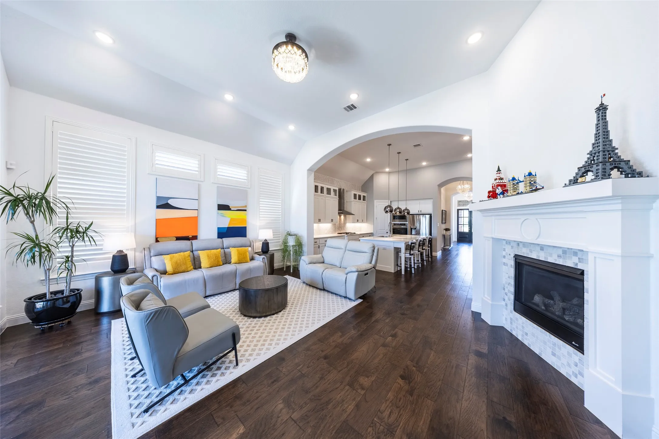 Living room with lofted ceiling, a tile fireplace, dark wood finished floors, recessed lighting, and arched walkways