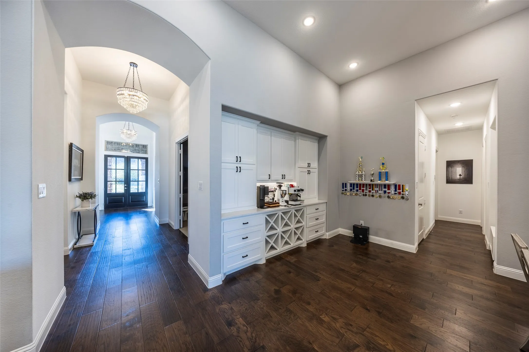 Hallway featuring arched walkways, dark wood-style flooring, a chandelier, and a towering ceiling