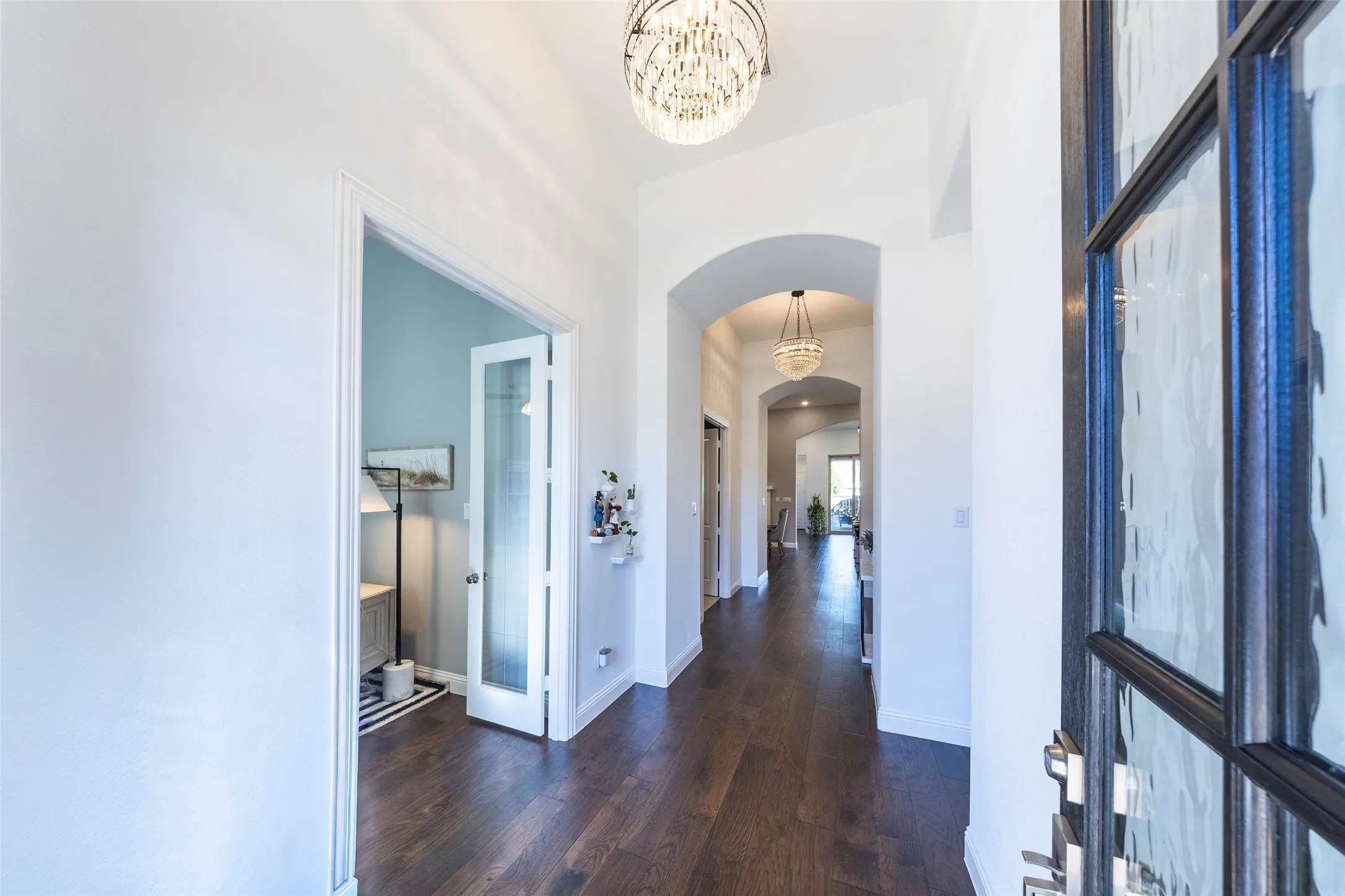 Corridor featuring arched walkways, dark wood finished floors, and a chandelier