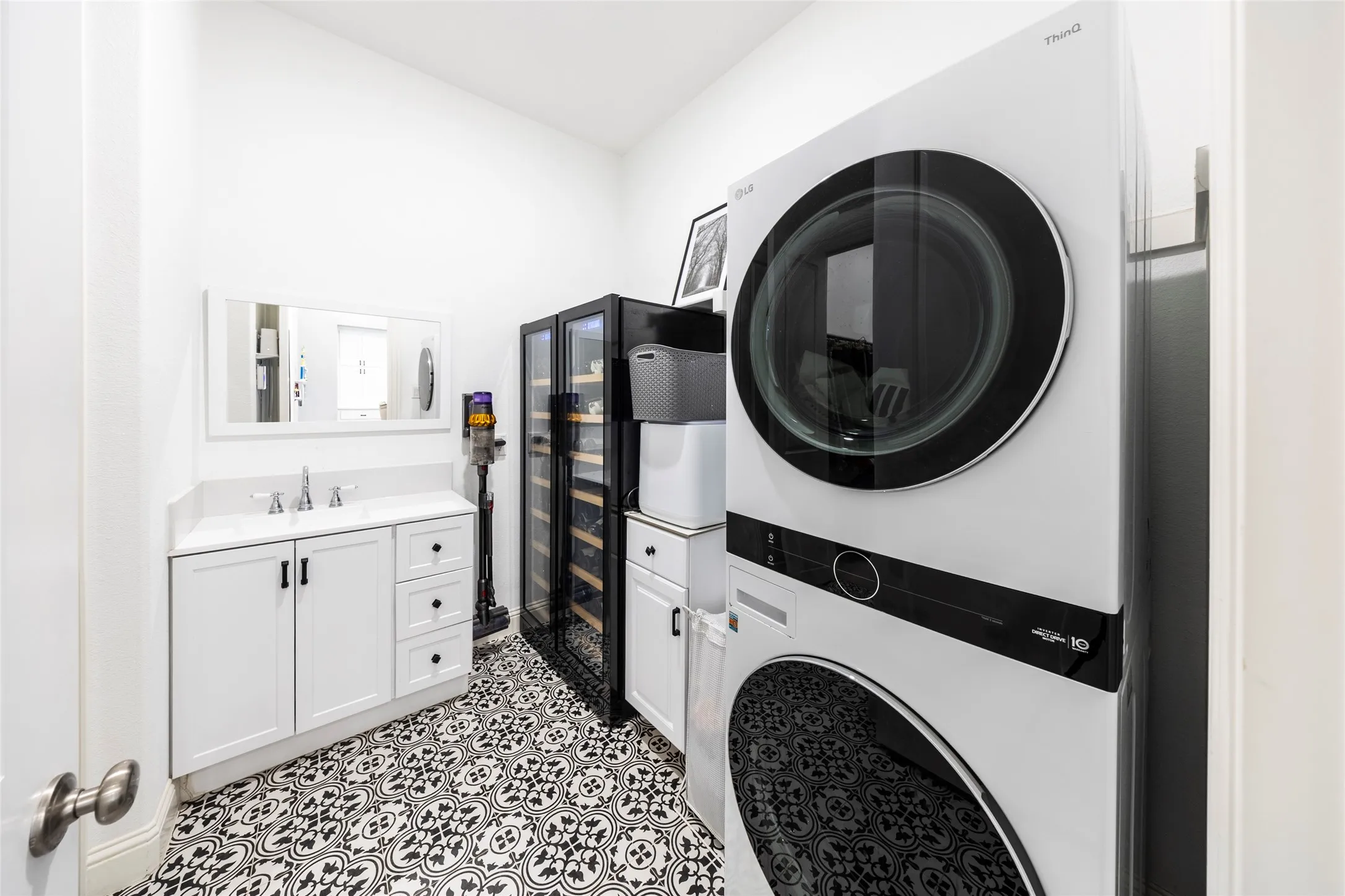 Washroom featuring stacked washer / drying machine and beverage cooler
