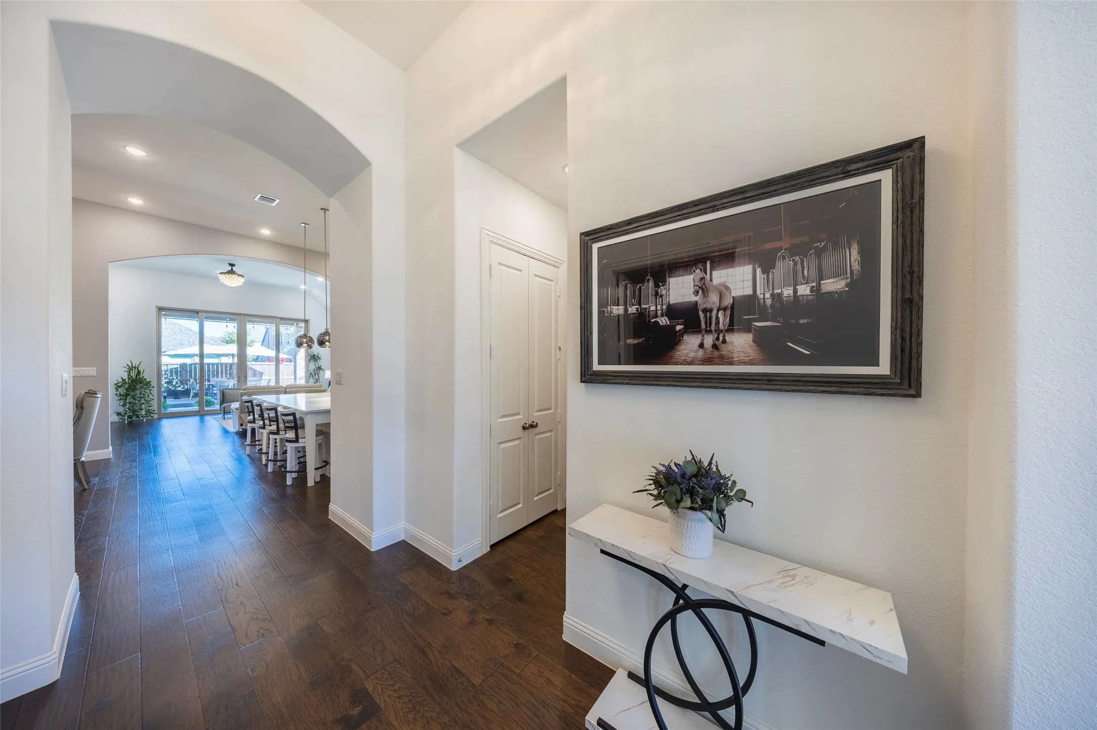 Hall with dark wood-style floors, arched walkways, and recessed lighting