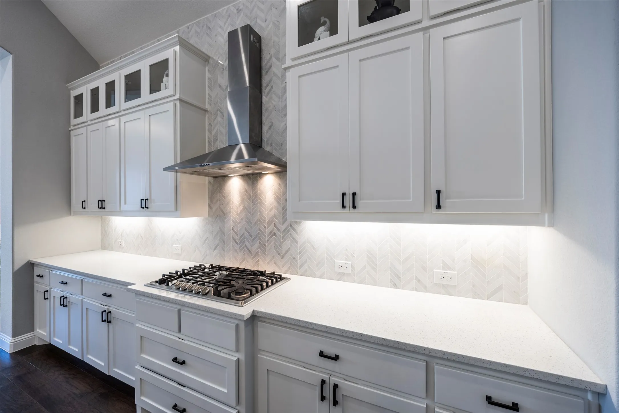 Kitchen featuring white cabinets, wall chimney range hood, decorative backsplash, and light stone countertops