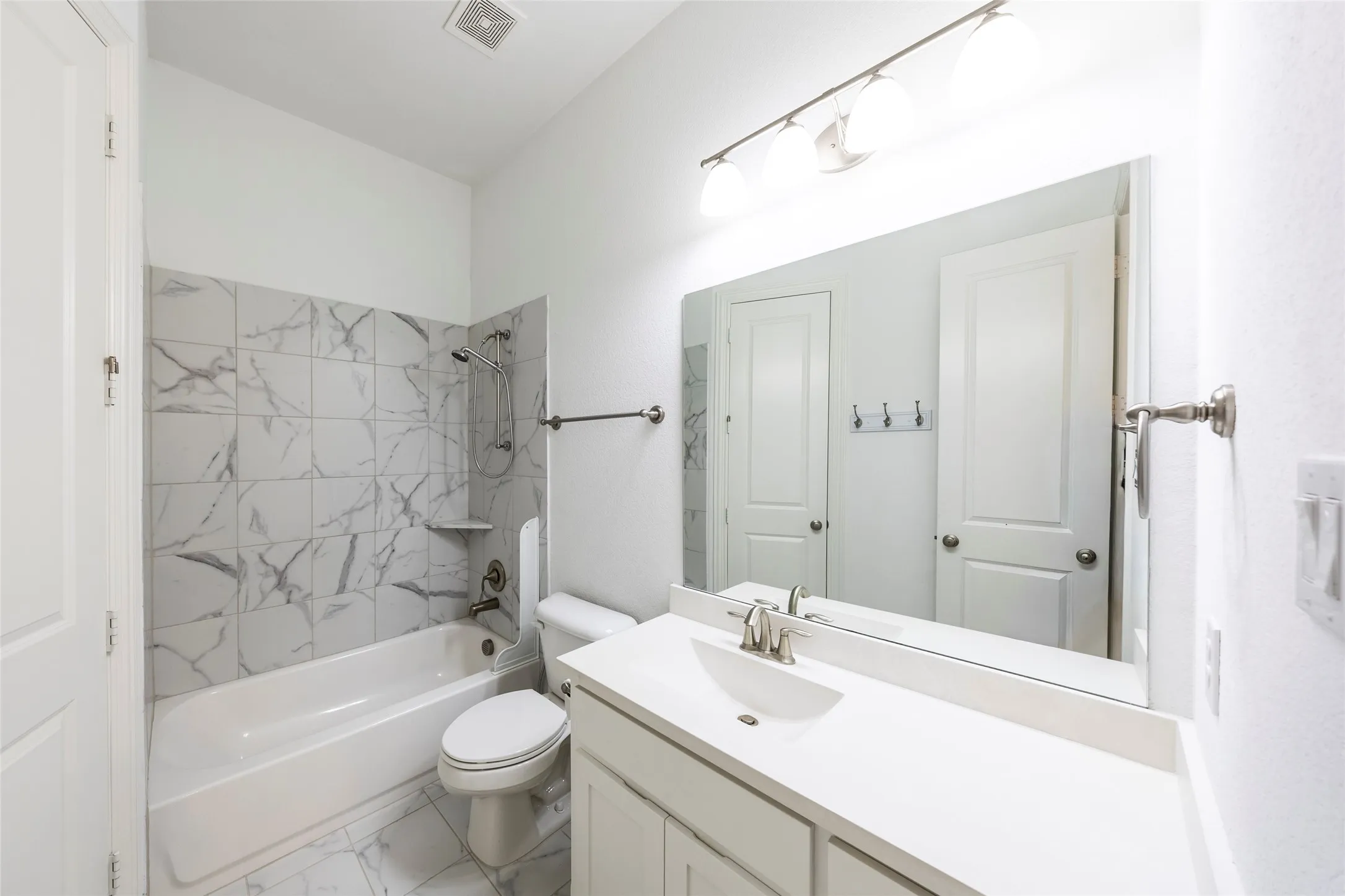 Bathroom featuring tub / shower combination, vanity, and marble look tile flooring