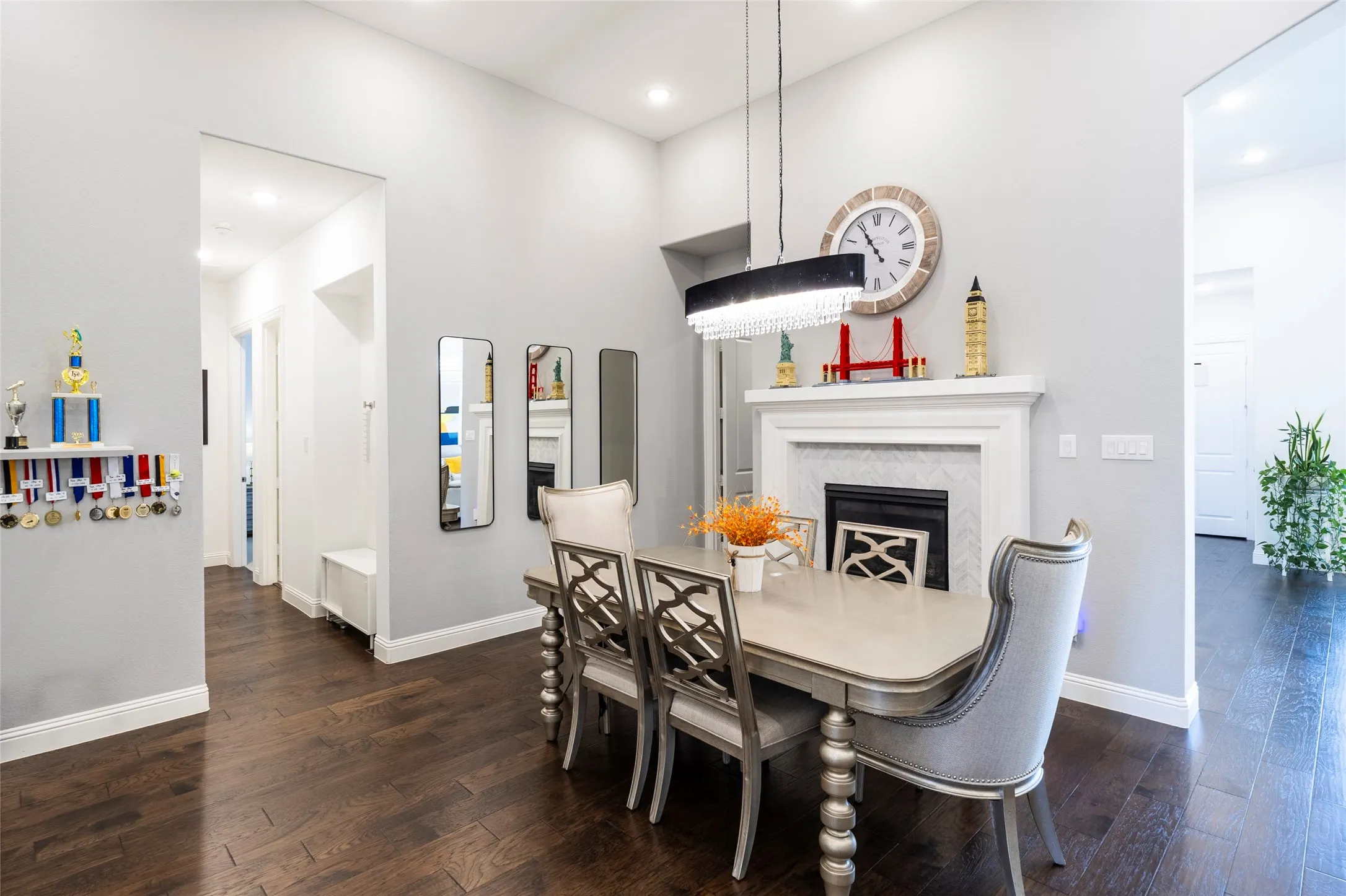 Dining room with a high end fireplace, dark wood-type flooring, and recessed lighting