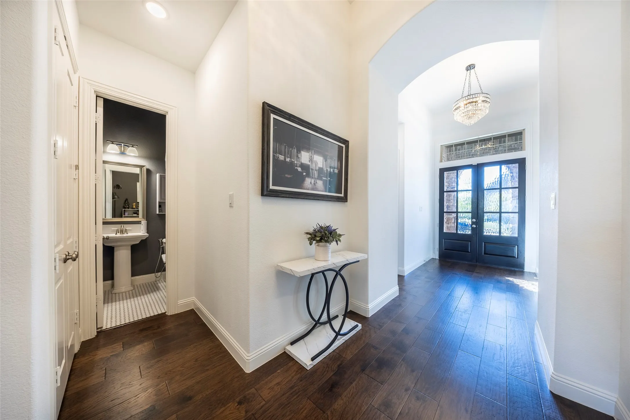 Hall with dark wood finished floors, french doors, and a chandelier