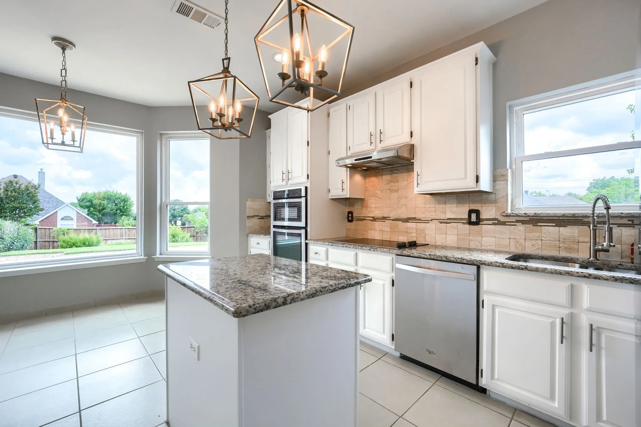 Kitchen featuring a central island with a granite countertop, white cabinetry, and stainless steel appliances
