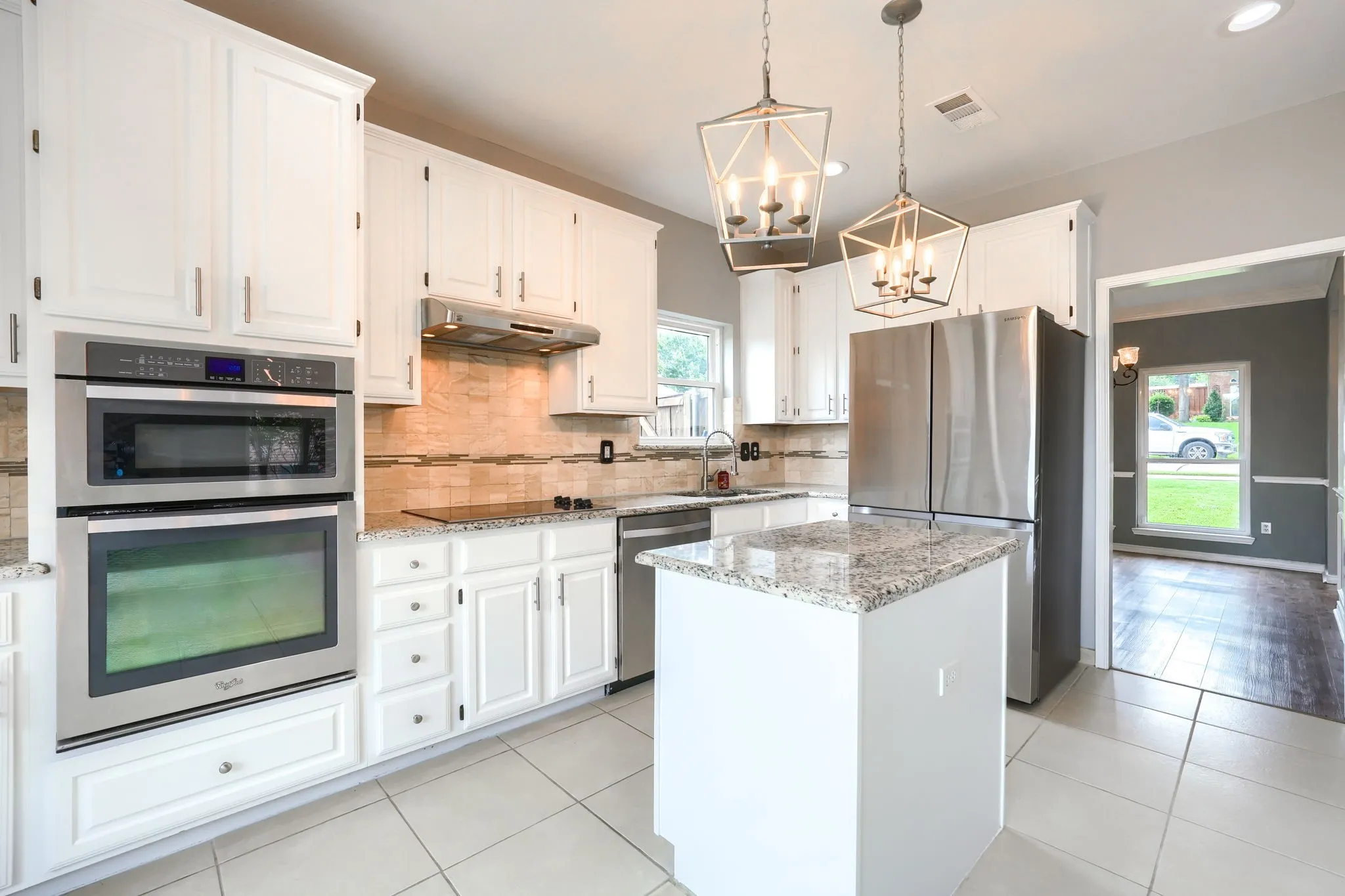 Kitchen featuring white cabinetry, stainless steel appliances, granite countertops, and an island
