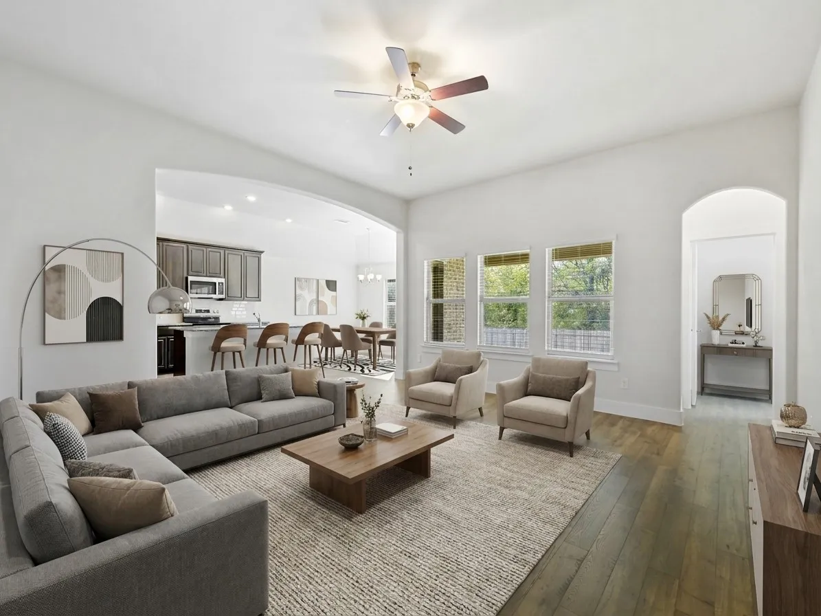 Spacious living area featuring high ceilings, wood-finish flooring, and multiple windows