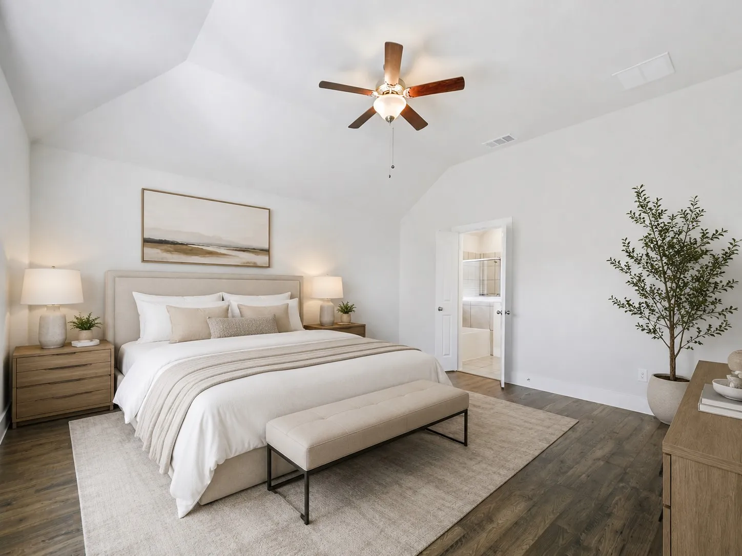 Vaulted ceilings featuring a ceiling fan, wood-finish flooring, and a white paneled door revealing a tiled bathroom with a tub
