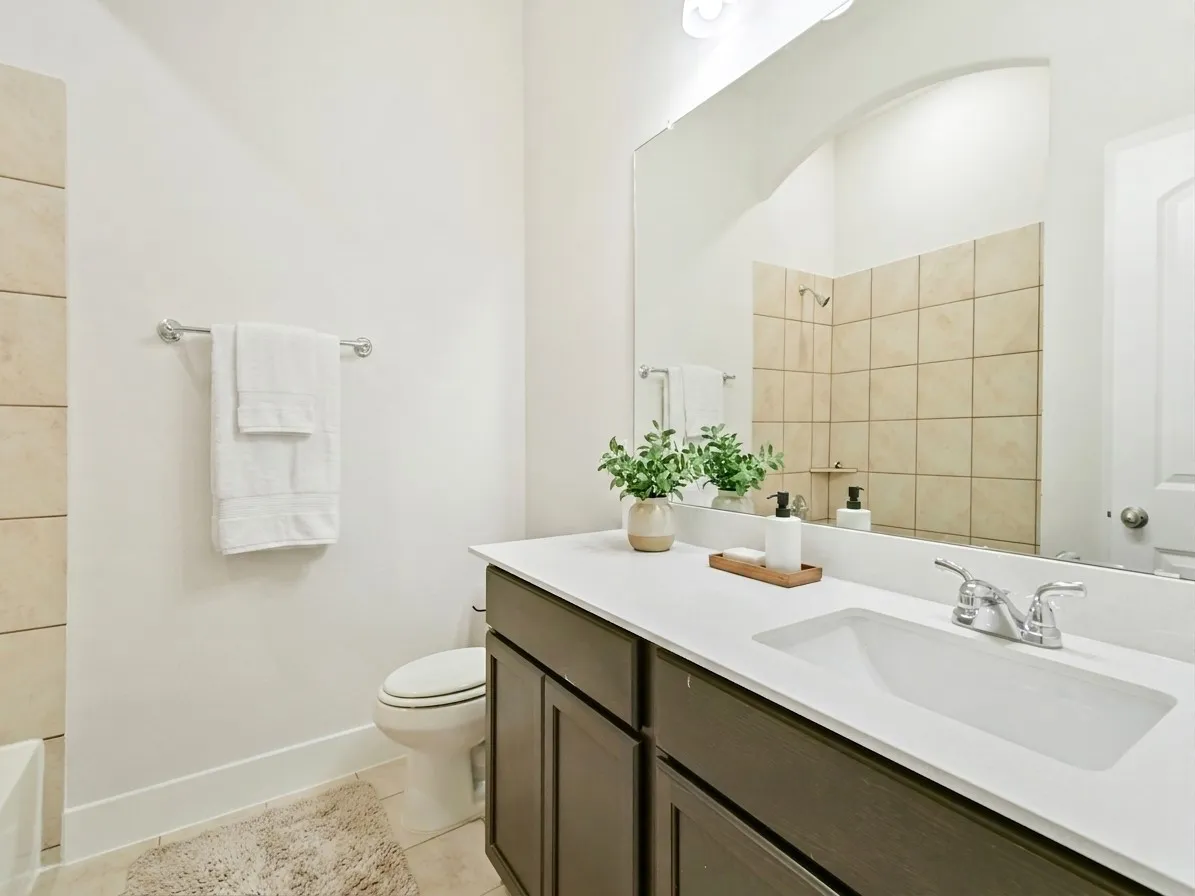 Bathroom featuring a dark wood-finish vanity with an integrated white sink, chrome faucet, and a large wall-mounted mirror