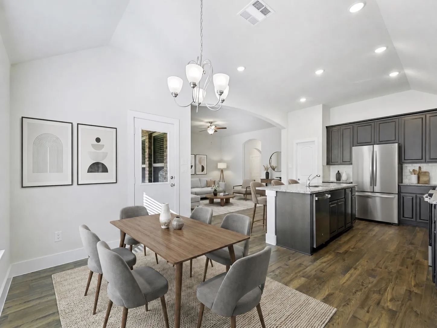Open-concept living space featuring vaulted ceilings, wood-finish flooring, and recessed lighting